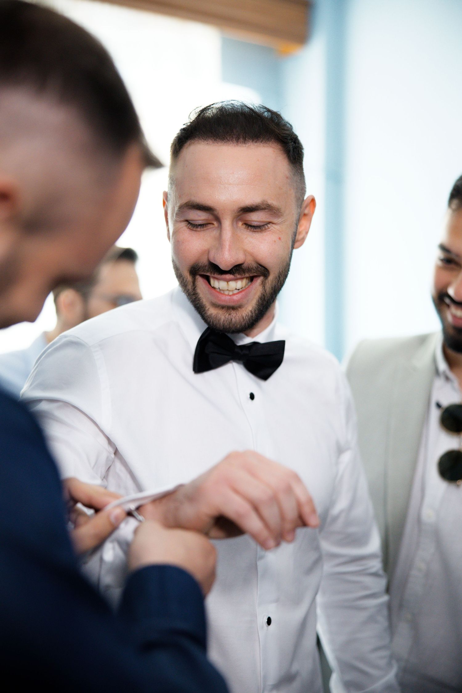 A happy moment between friends getting ready in formal attire with bow ties and white dress shirts.