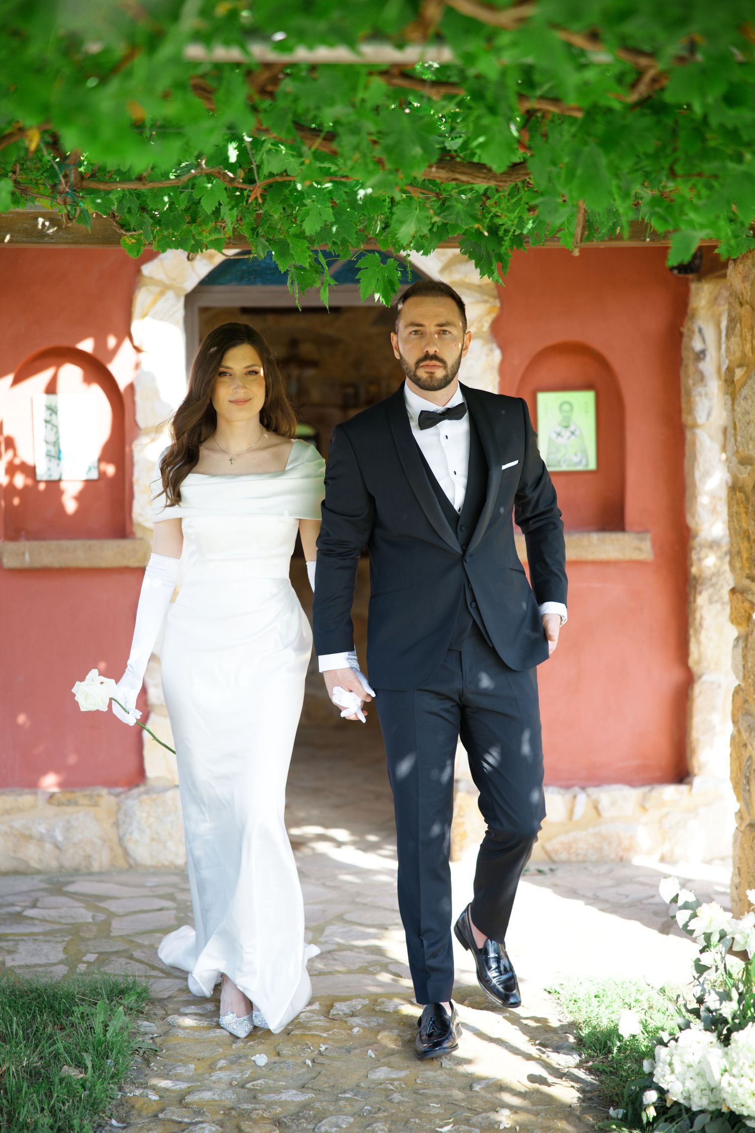 Romantic wedding portraits captured along a Mediterranean-style stone walkway with lush foliage.