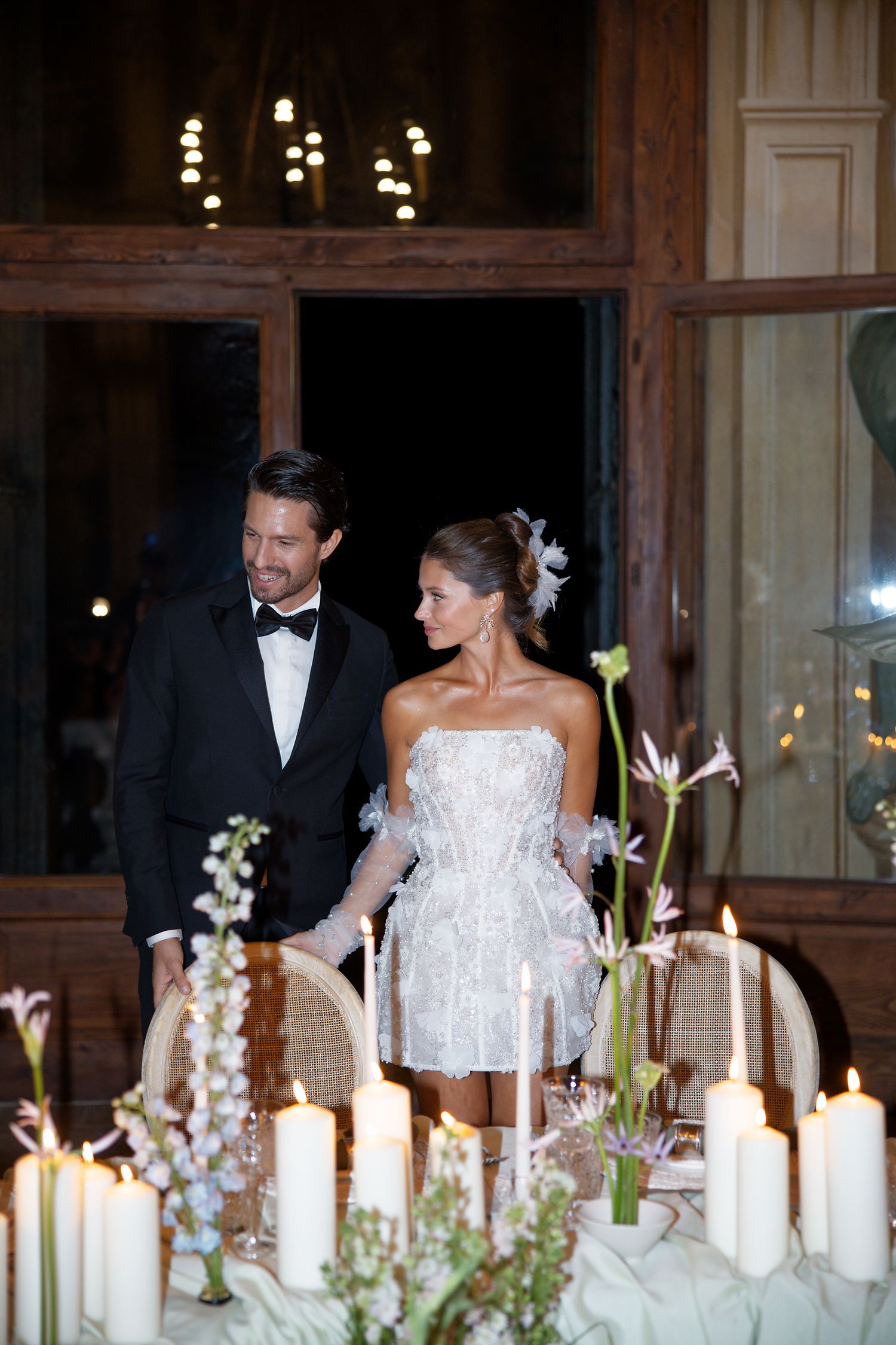 Elegant wedding reception setup with white candles and floral arrangements on a formal dining table.