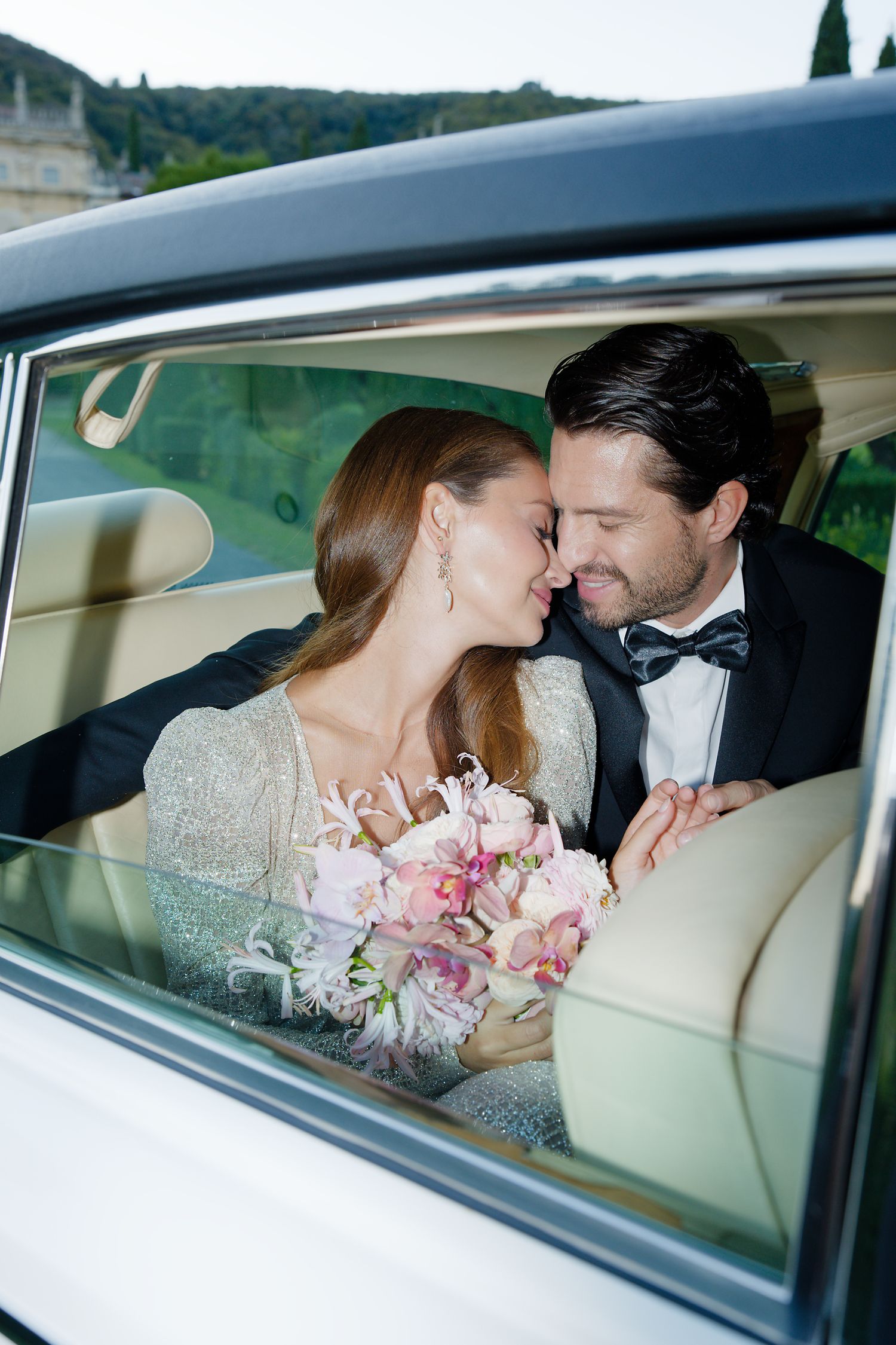 Elegant wedding couple sharing an intimate moment in a luxury car.