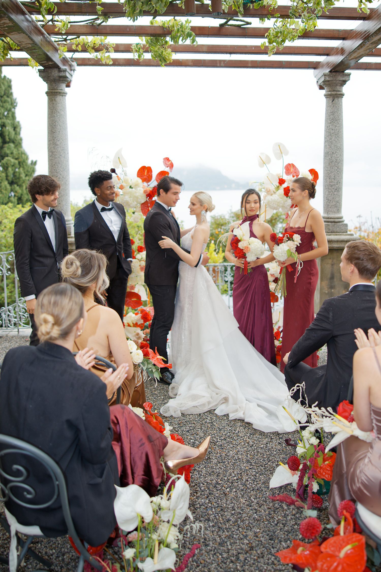 Wedding ceremony held under pergola with vibrant orange floral decorations.