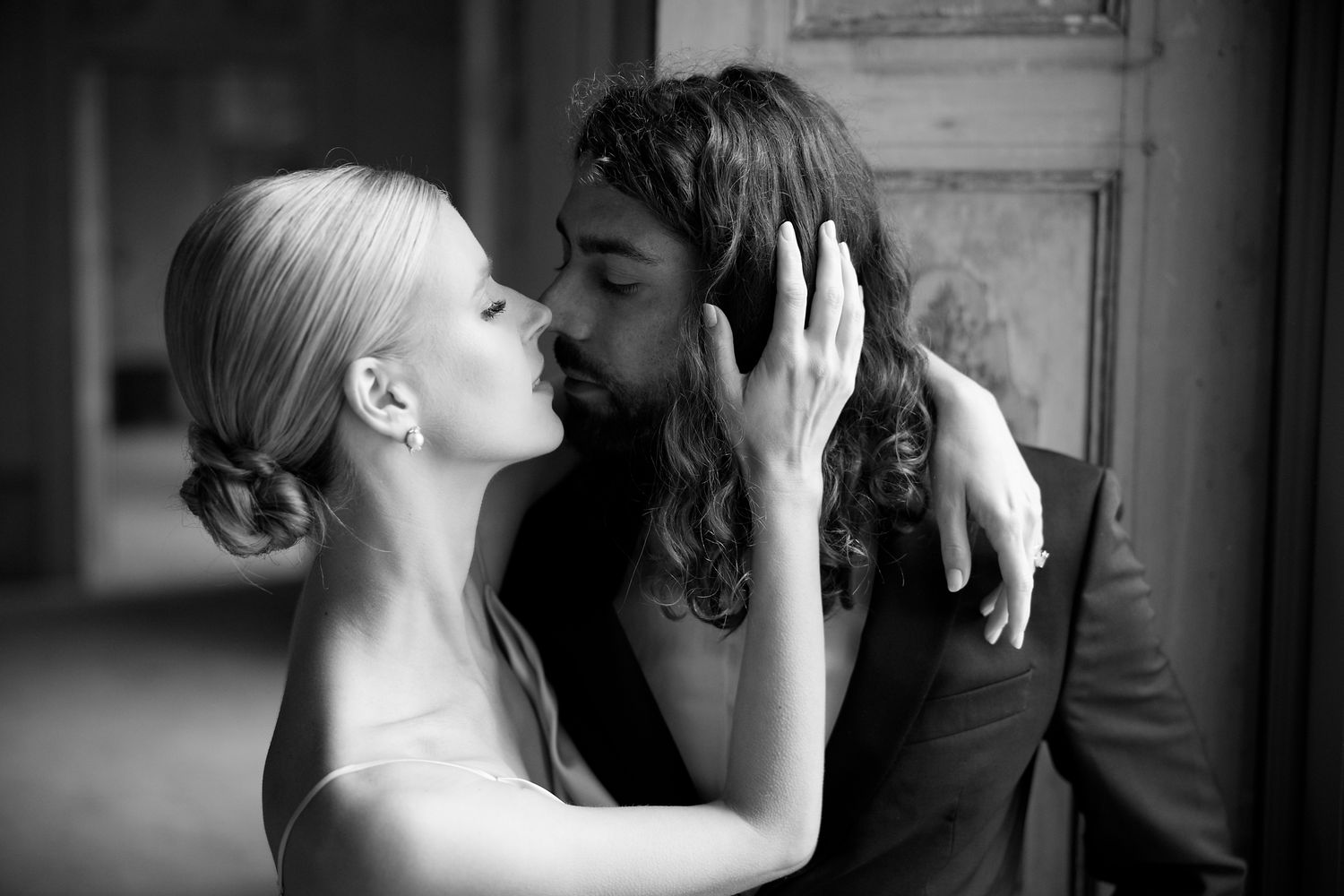 An intimate black and white portrait captures a romantic moment between a couple in formal attire.