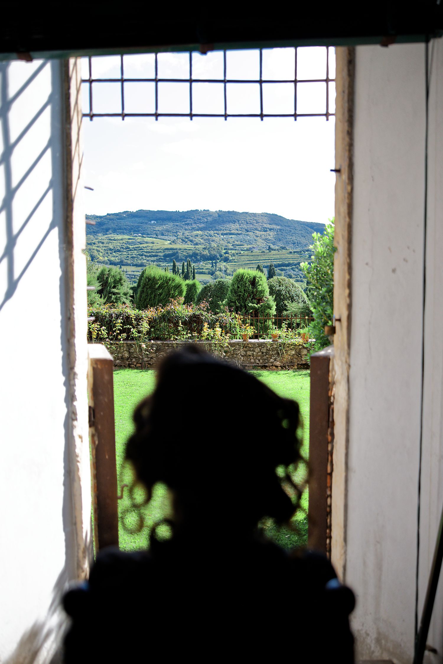 Scenic rolling hills and countryside viewed through a rustic window frame casting dramatic shadows.