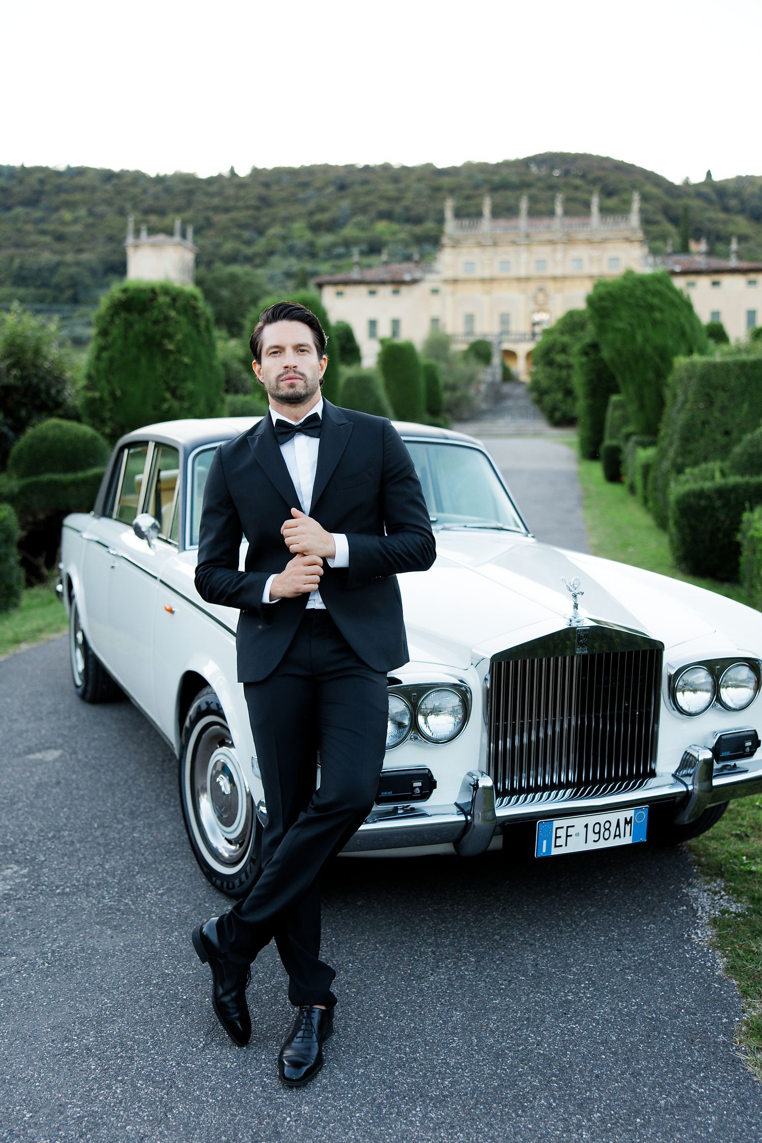 Luxury white vintage Rolls-Royce against the backdrop of a grand Italian villa.