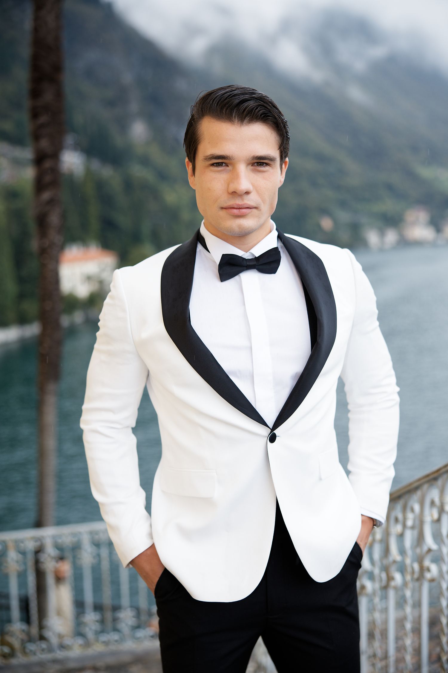 Classic white tuxedo jacket with black lapels photographed against scenic Lake Como background.