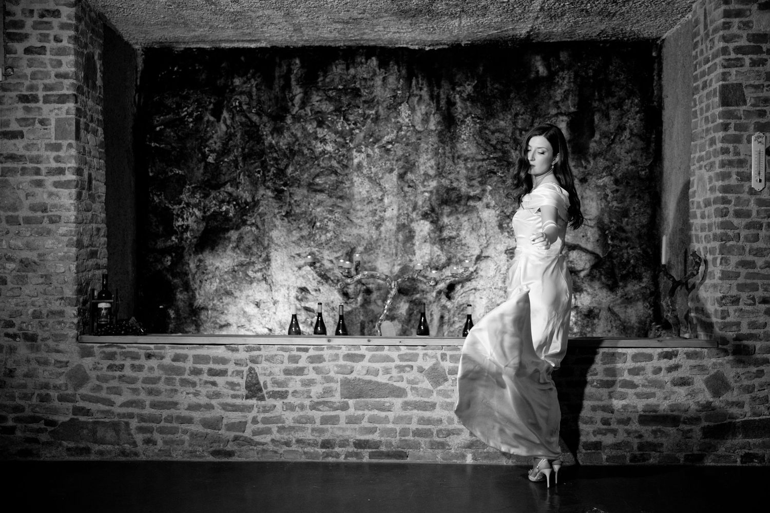 Artistic black and white photographs against a textured brick wall create a dramatic wedding scene.