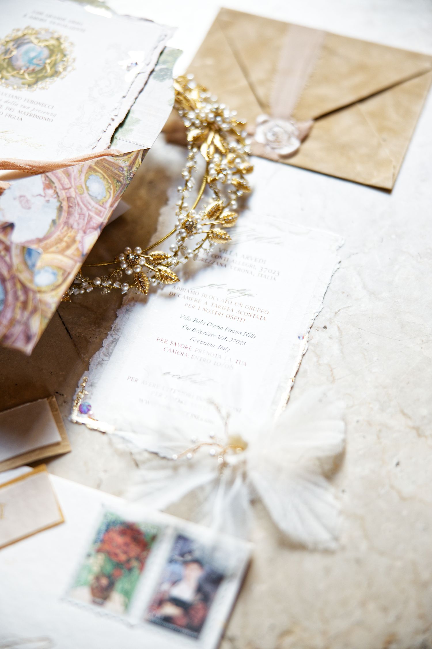 Vintage wedding stationery arrangement with gold crown and romantic envelopes adorned with delicate stamps and floral designs.
