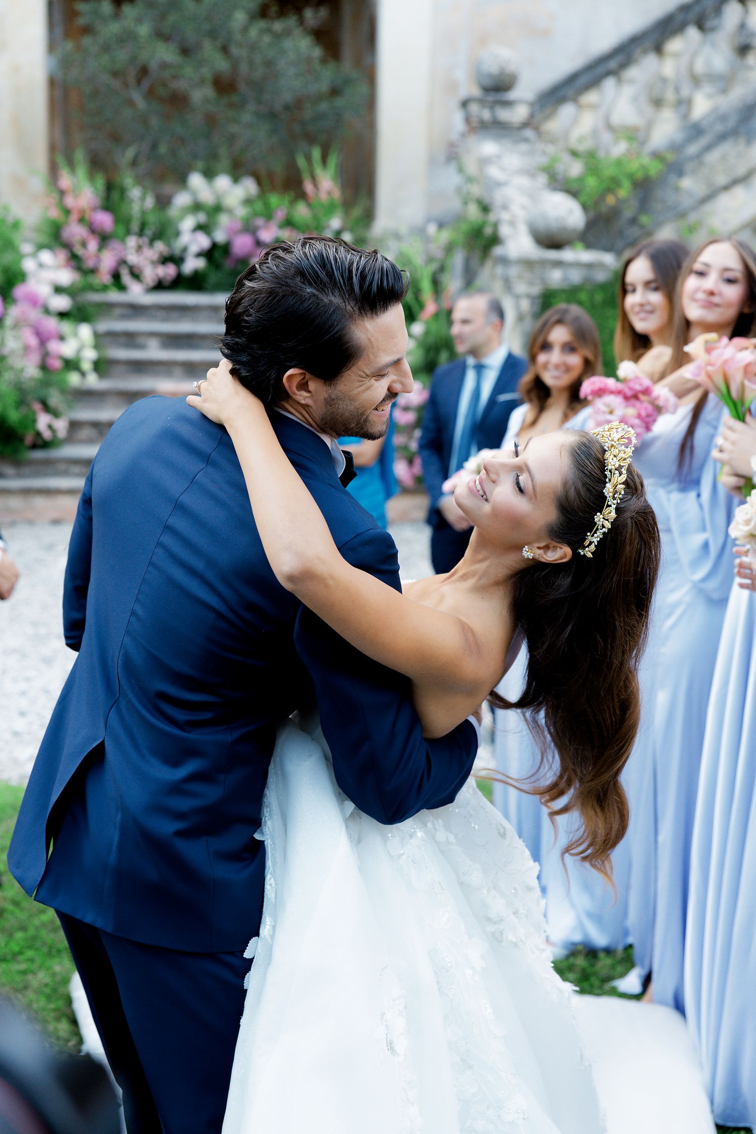 Romantic wedding couple embracing and dancing surrounded by bridesmaids in light blue dresses.