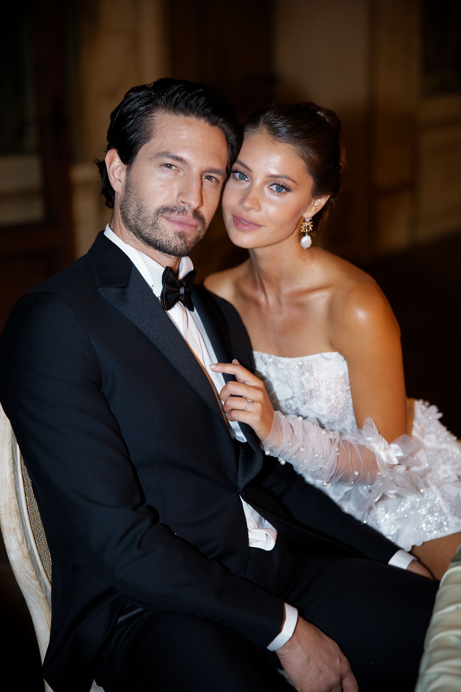 Elegant couple in formal black tie attire and white gown posing at a luxury event.