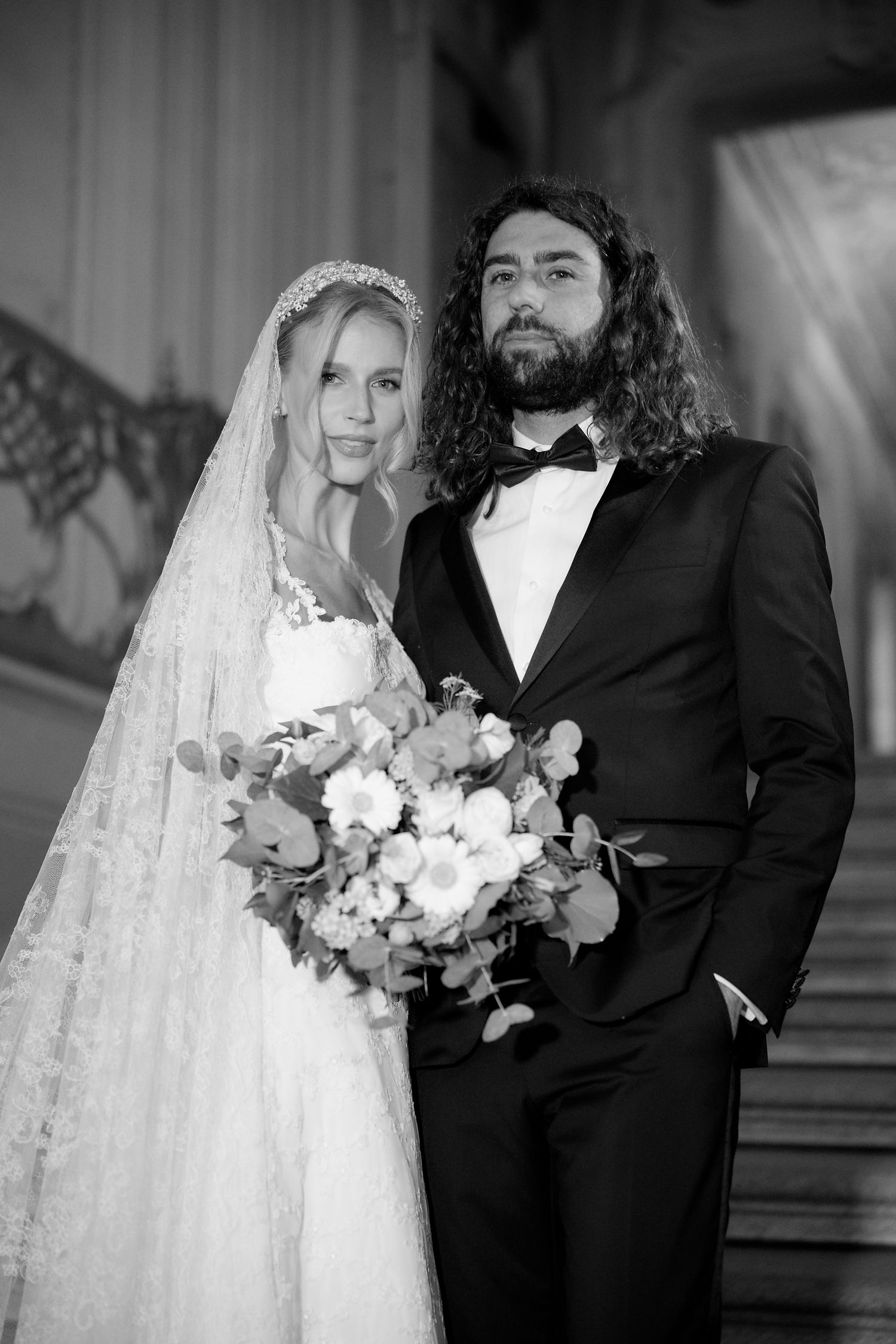 A black and white wedding photo shows a couple, with the bride in a veil and gown holding flowers, and groom in a tuxedo.