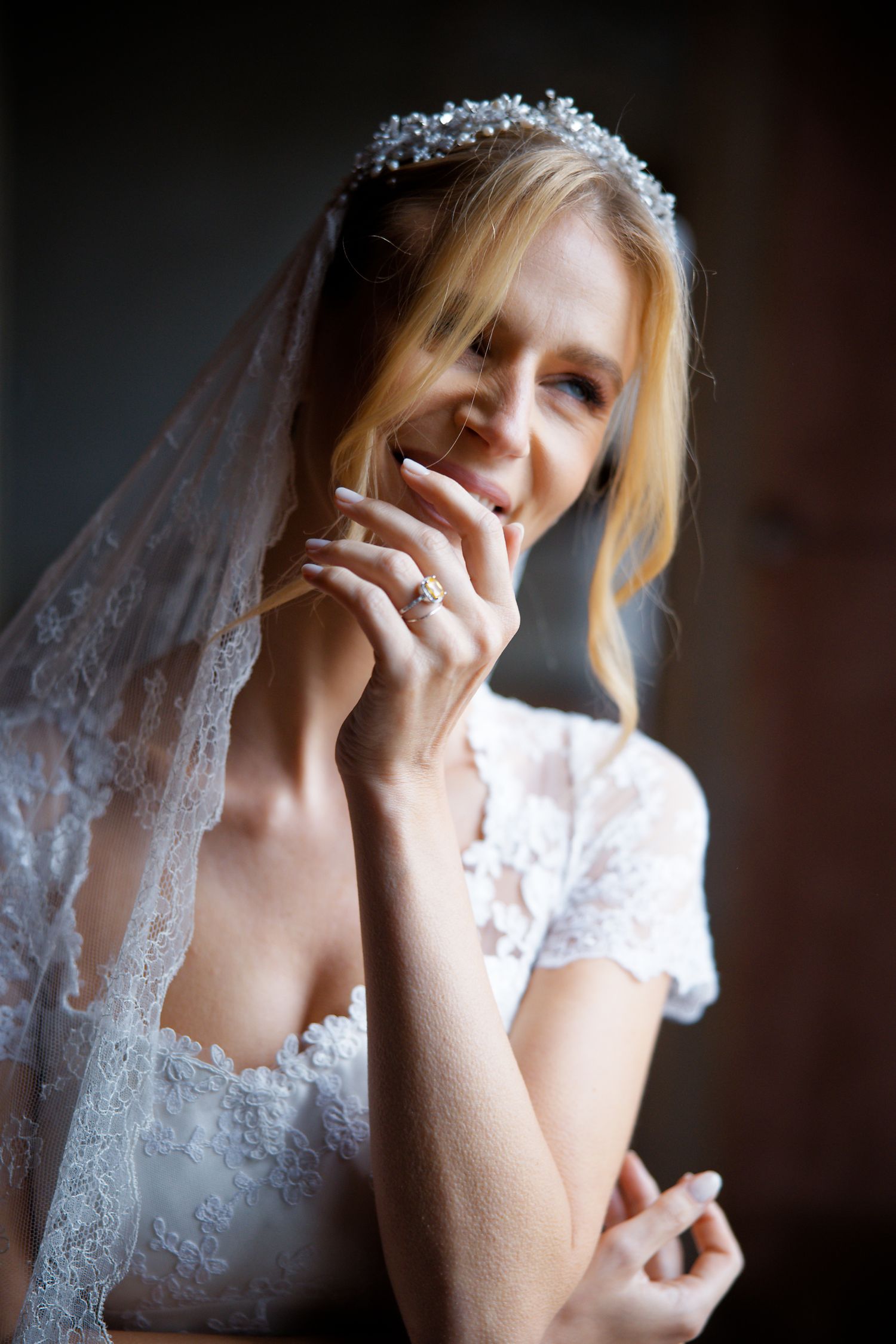 A joyful wedding portrait showing the bride's crystal headpiece, lace veil and elegant white gown.