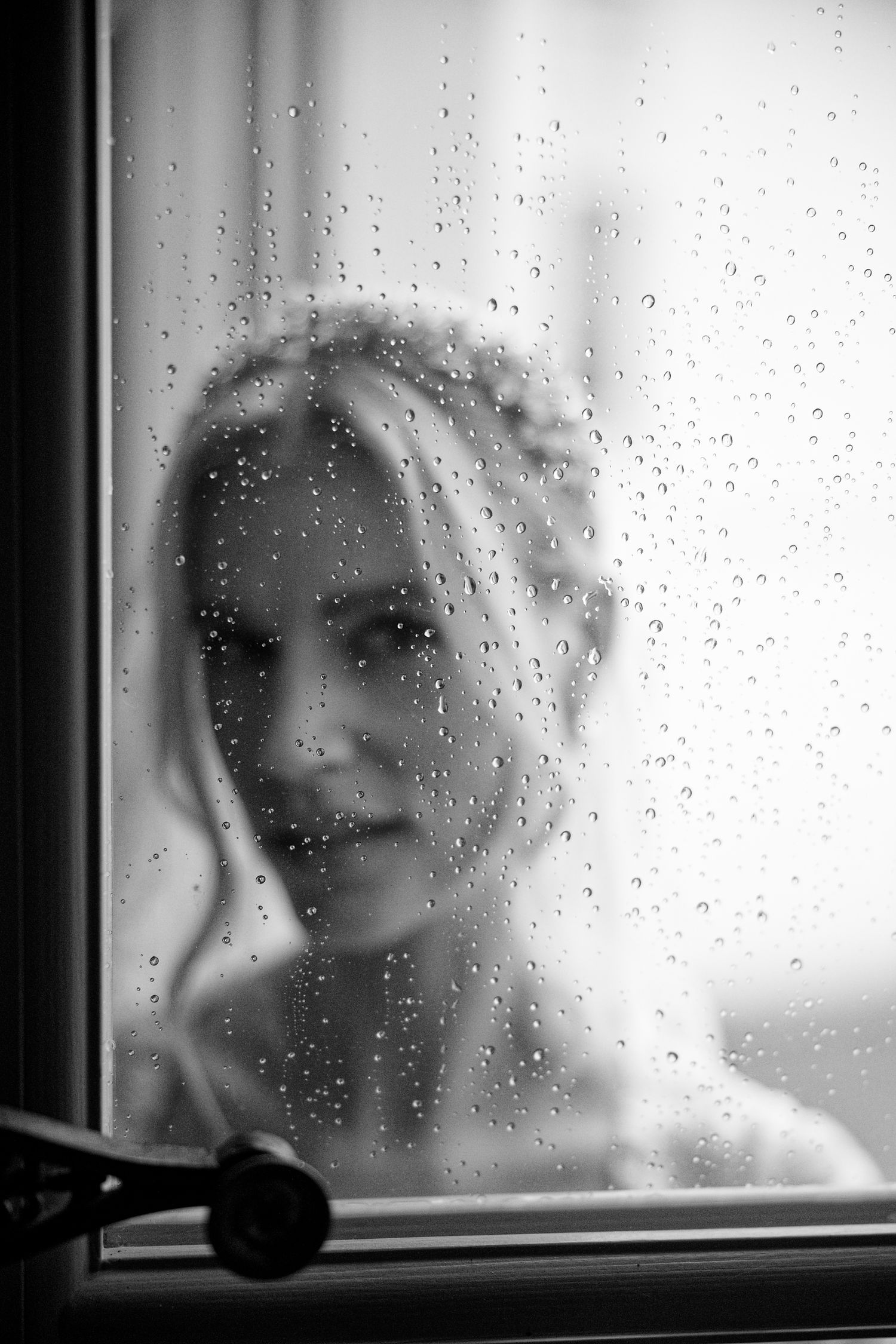 Condensation drops on a window pane create a dreamy, soft-focus monochrome effect on a rainy day.