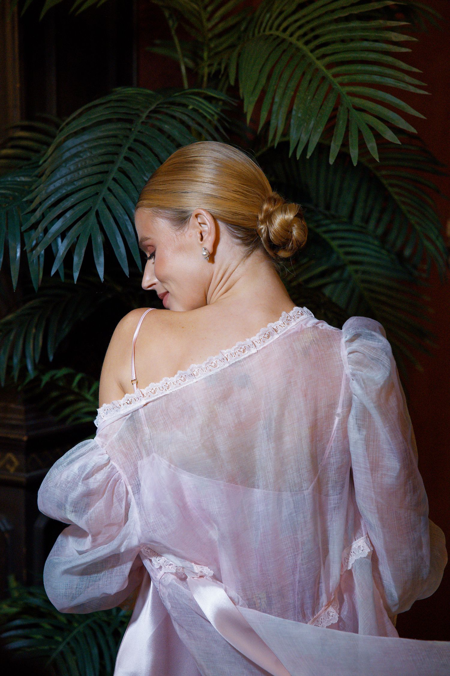 Back view of delicate pink silk dress with puff sleeves among palm fronds.