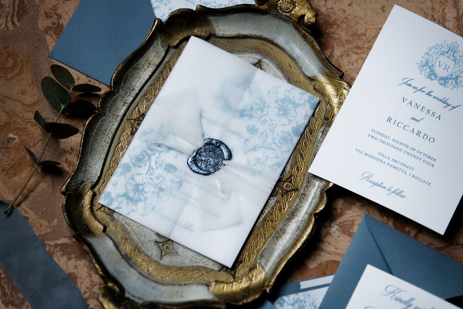 Elegant wedding invitation with blue wax seal on antique silver tray.