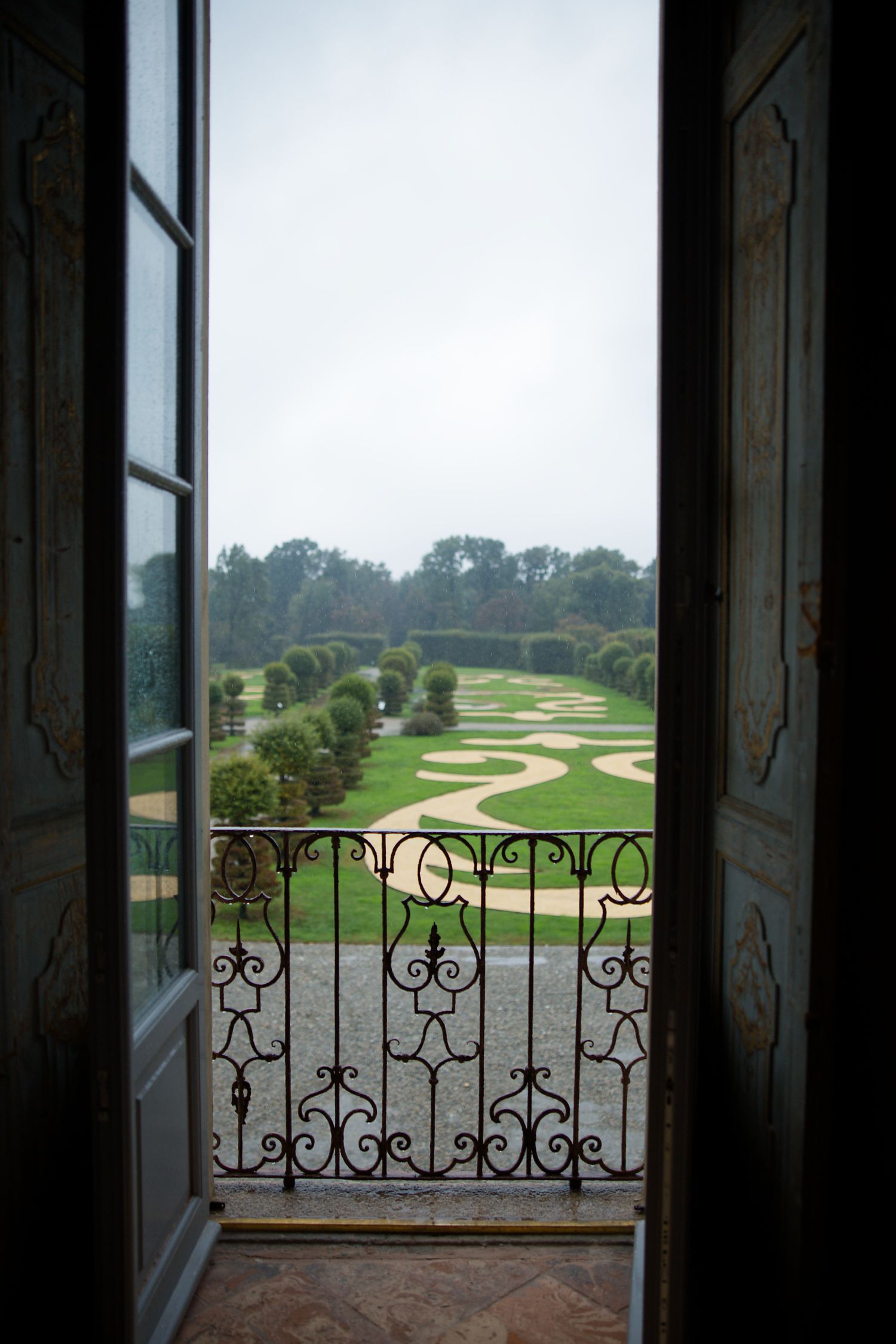 View through an ornate window reveals a winding golf course path through lush green landscape.