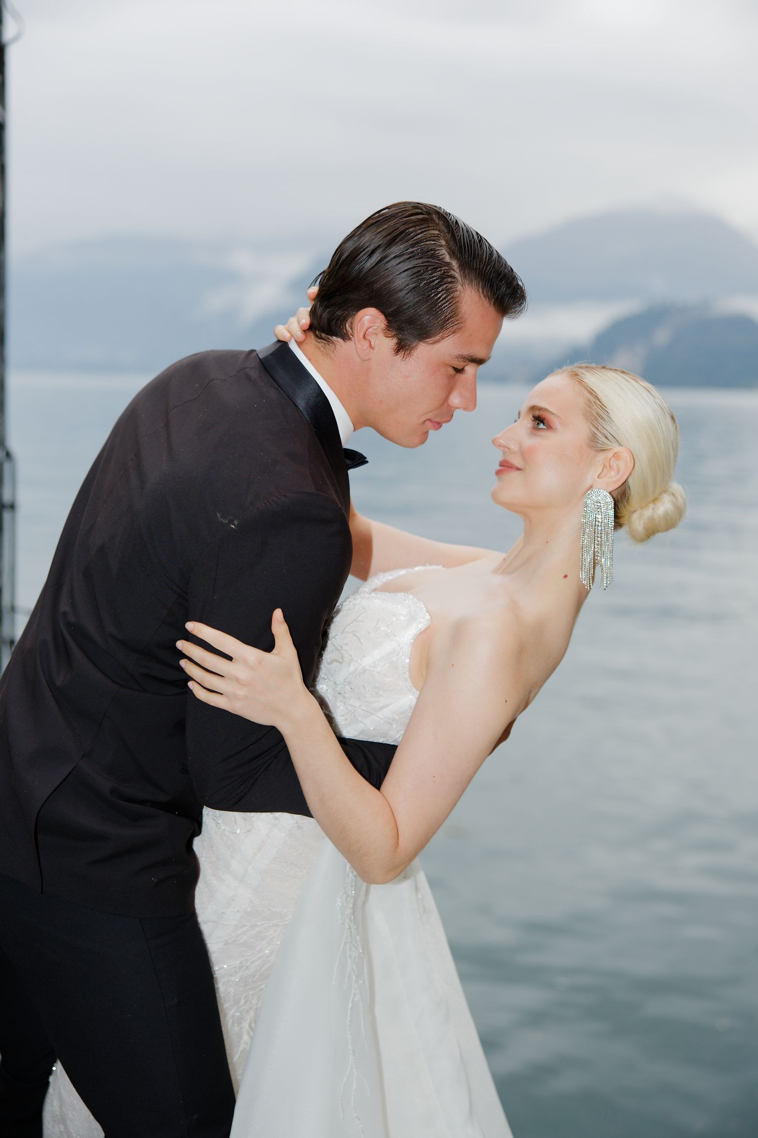 Romantic wedding portrait by a lake with mountains in the background.