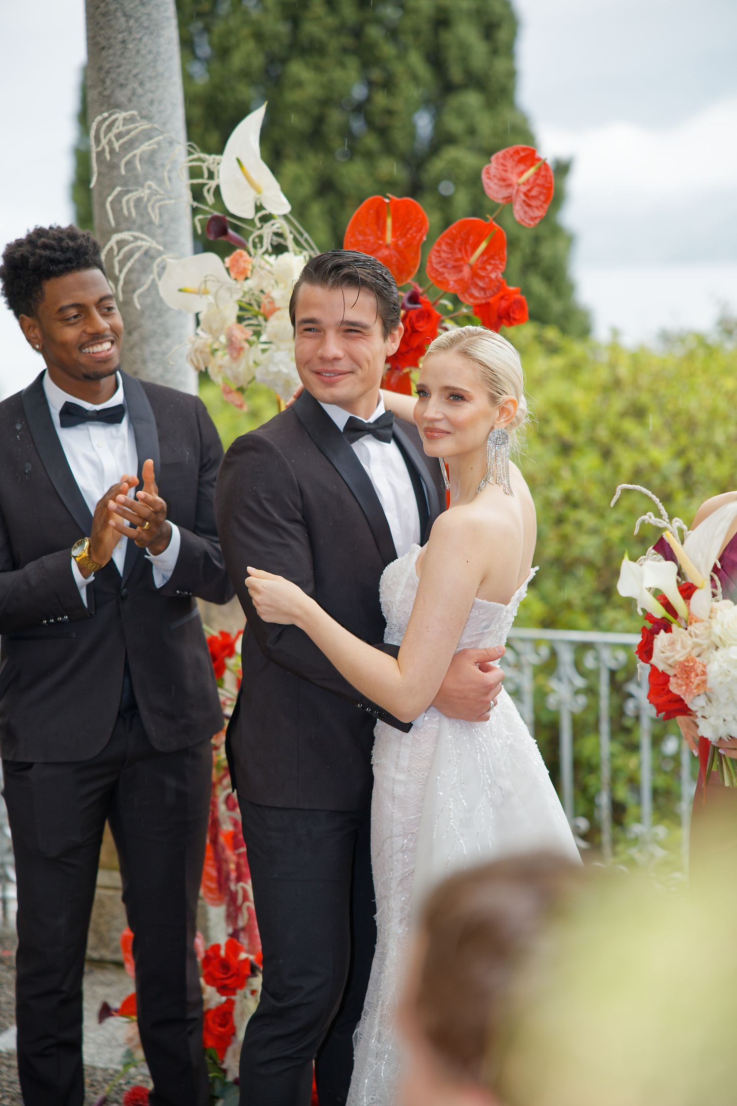 Wedding party celebrates during outdoor ceremony with bright floral arrangements and lake views.