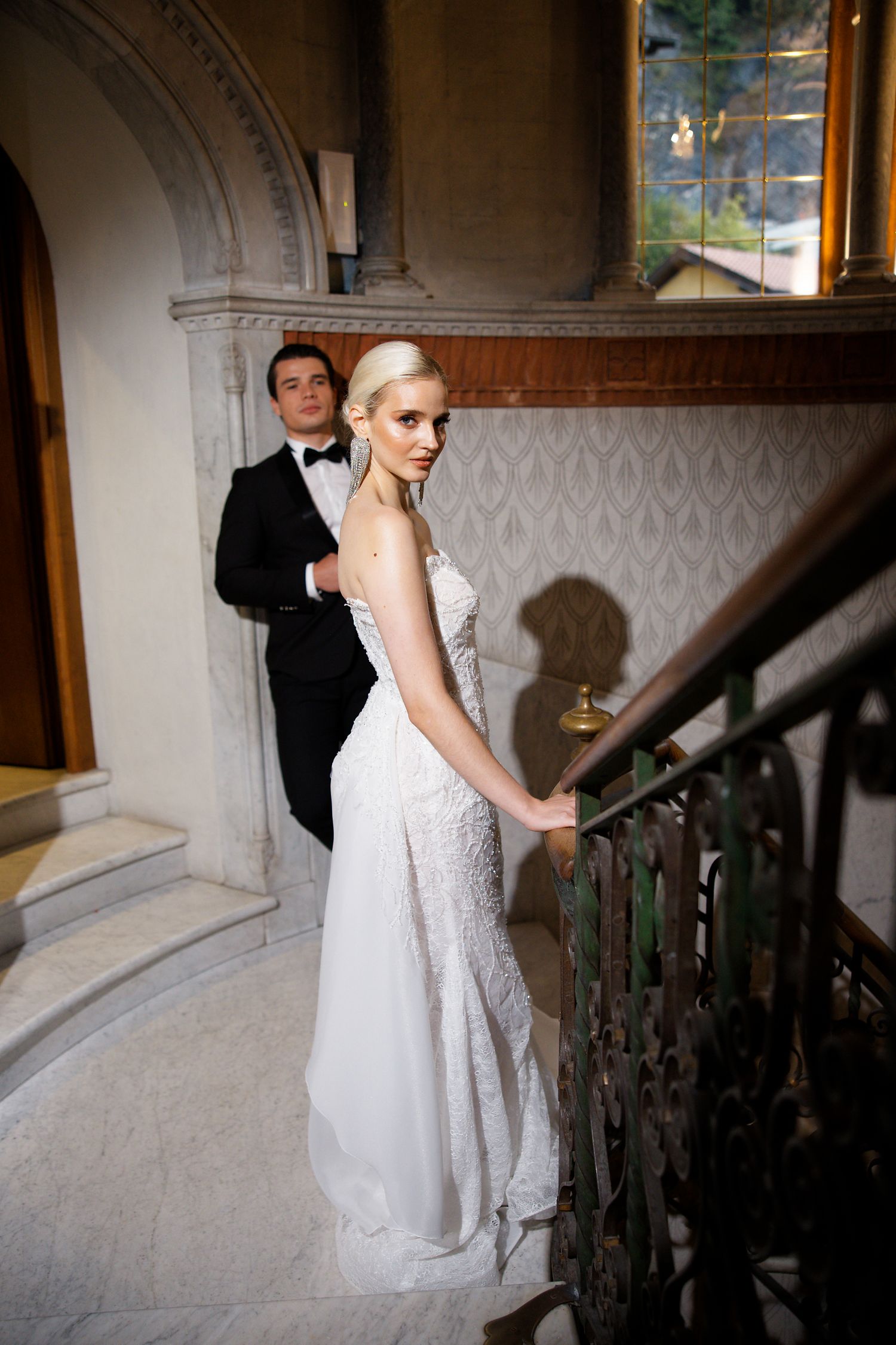 Elegant wedding photo on vintage marble staircase with ornate architectural details.