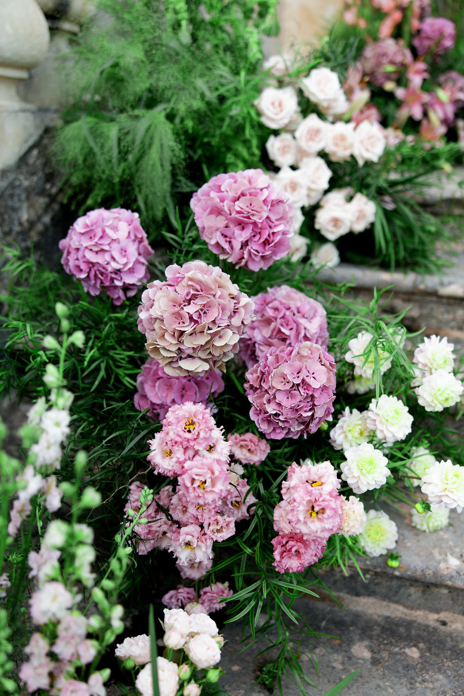 Pink and white carnations blooming on stone steps in a lush garden setting.