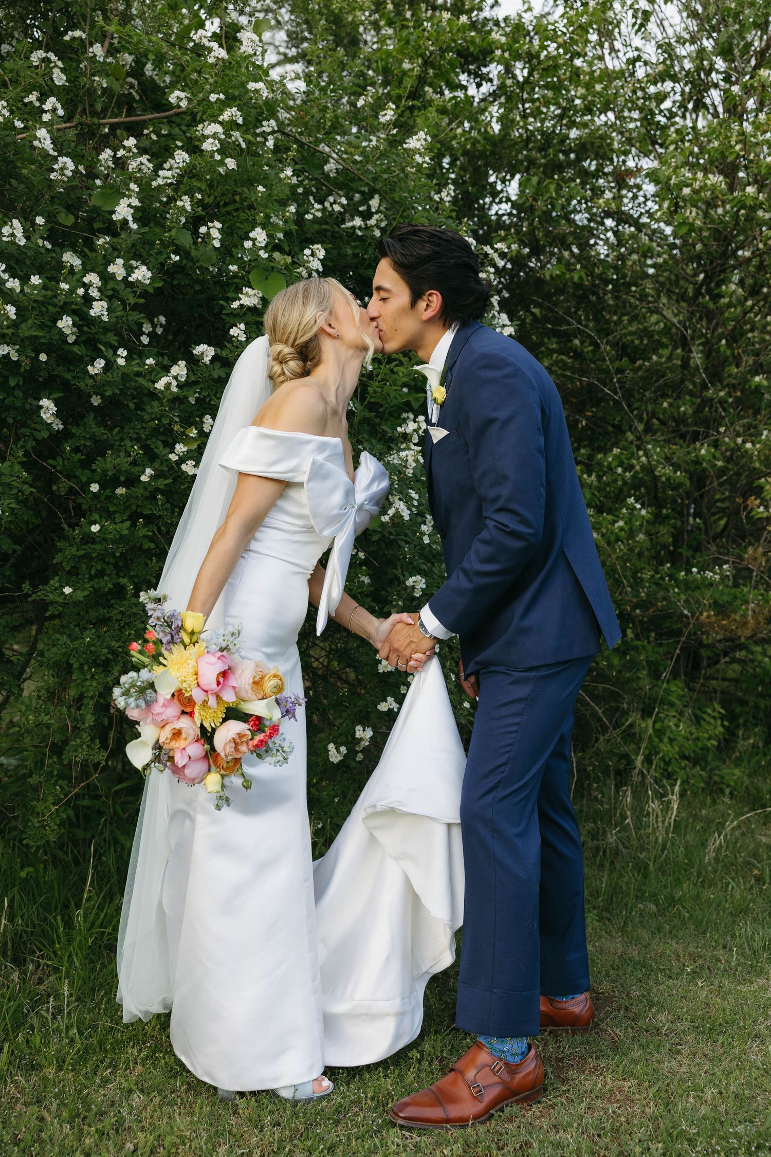 Birmingham Alabama Photographer capturing bride and groom kissing, in a field, at Iris Woods Venue in Nashville, Tennessee