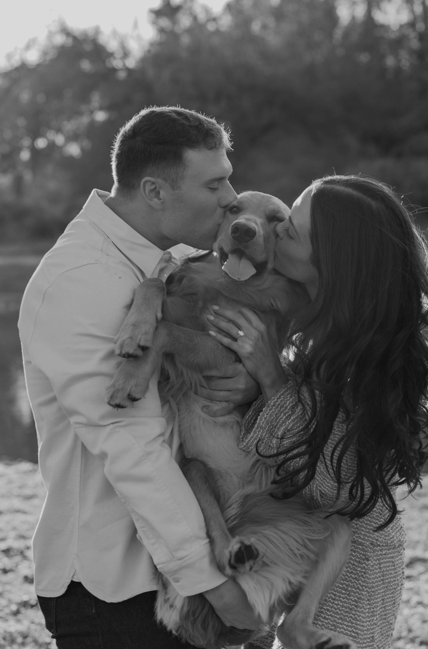 Birmingham Alabama Photographer capturing an engagement session of a couple kissing a golden retriever in a park in Nashville Tennessee