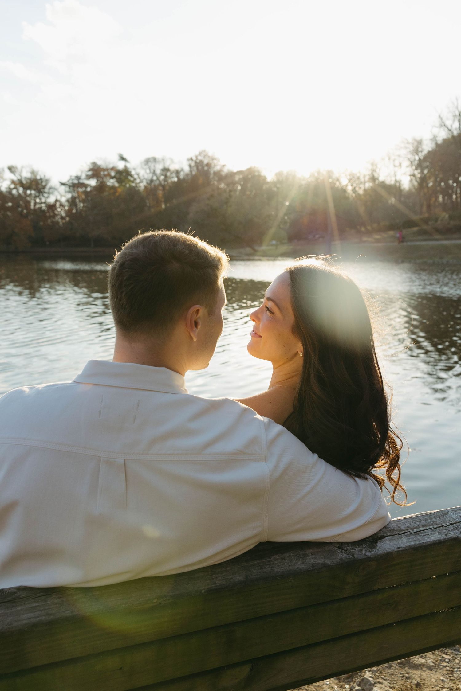 Birmingham Alabama Photographer capturing an engagement session of a couple smiling on a bench in a park by a lake in Nashville Tennessee