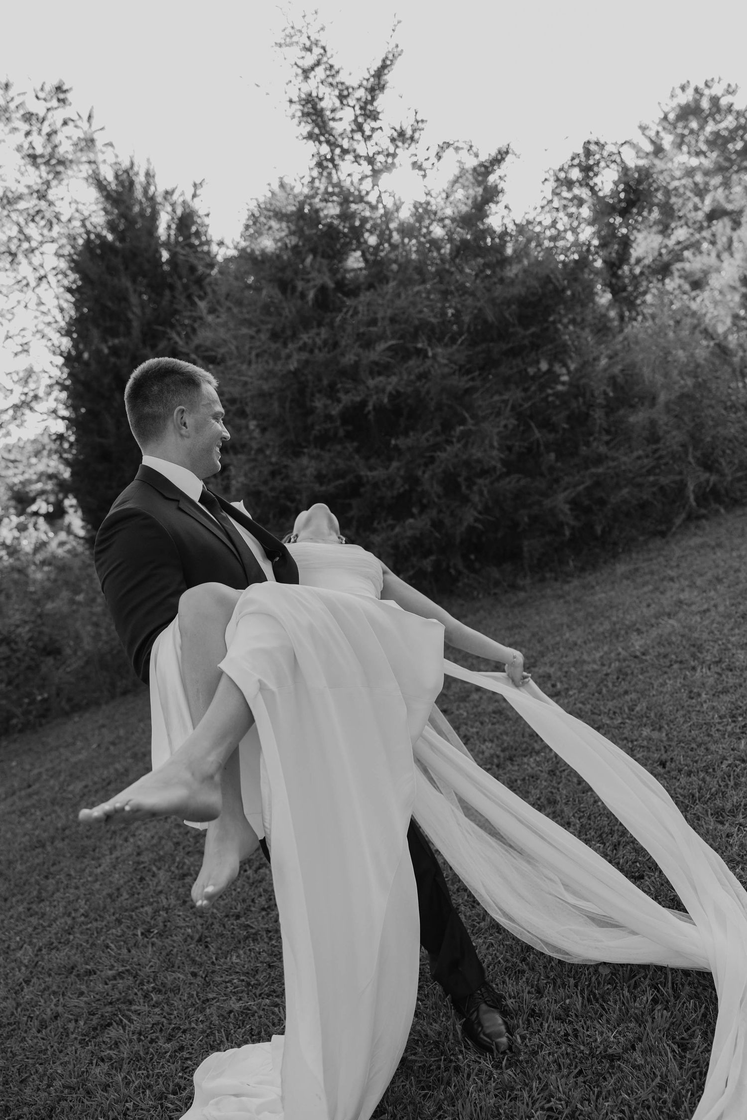 Birmingham Alabama Photographer capturing groom holding bride in a field, at Iris Woods Venue in Nashville, Tennessee