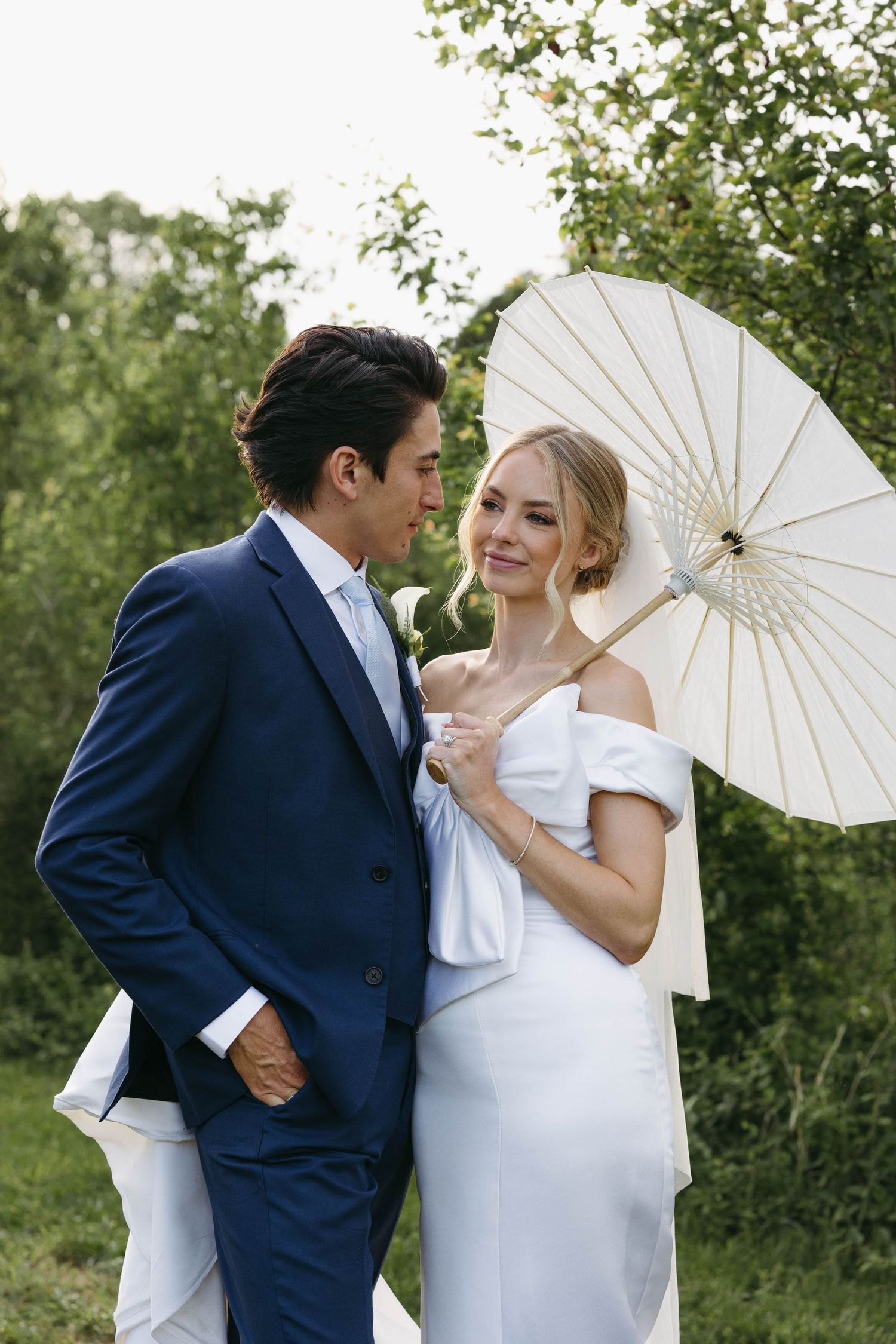 Birmingham Alabama Photographer capturing bride and groom smiling holding a parasol, in a field, at Iris Woods Venue in Nashville, Tennessee