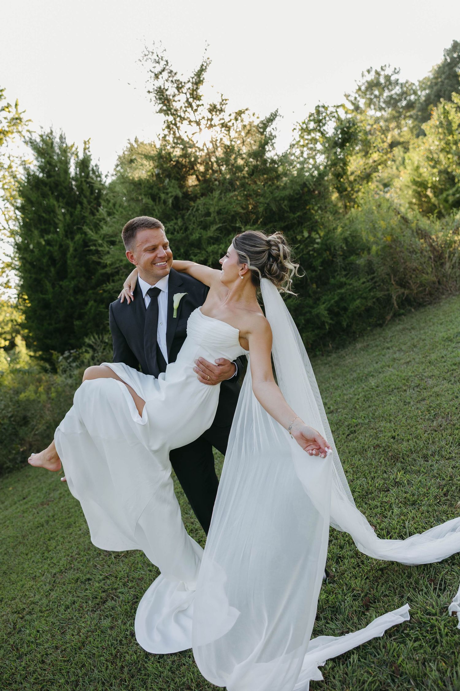 Birmingham Alabama Photographer capturing groom holding bride in a field, at Iris Woods Venue in Nashville, Tennessee