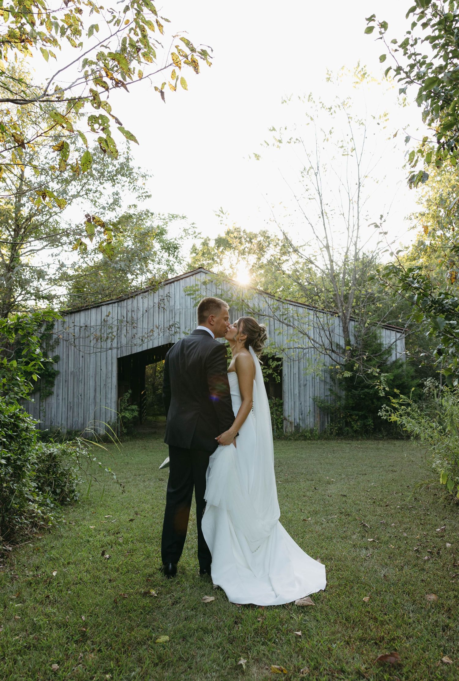 Birmingham Alabama Photographer capturing bride and groom kissing in a field, at Iris Woods Venue in Nashville, Tennessee