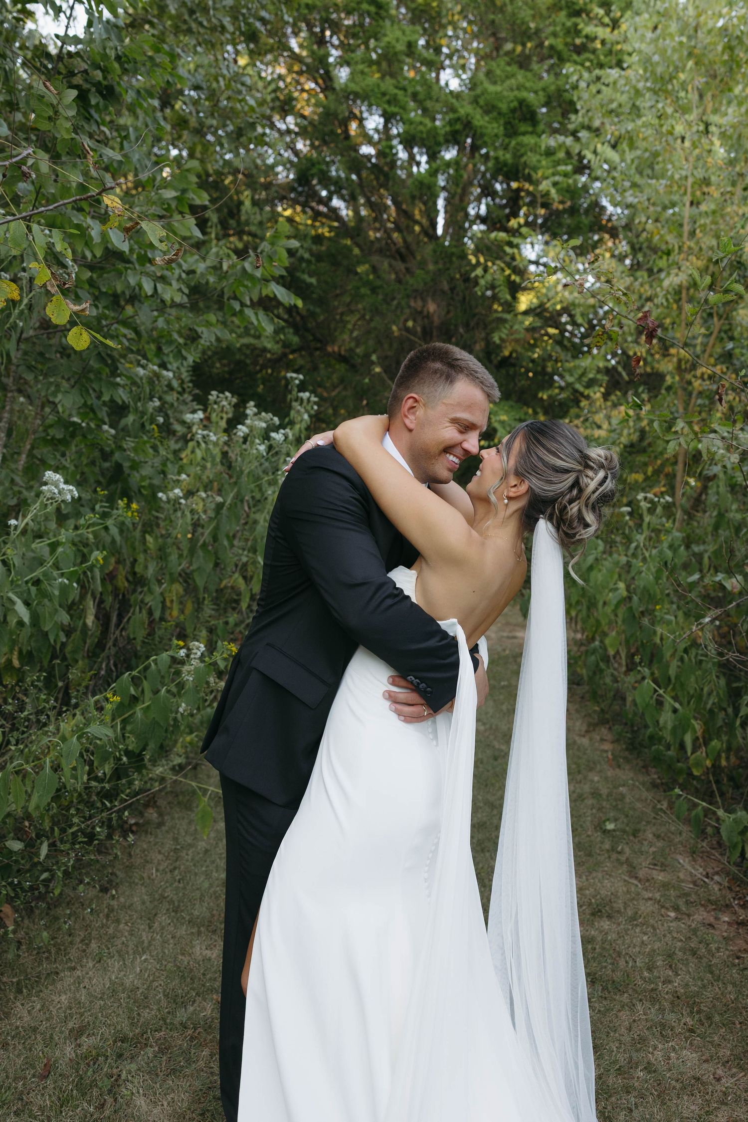 Birmingham Alabama Photographer capturing bride and groom kissing in a field, at Iris Woods Venue in Nashville, Tennessee