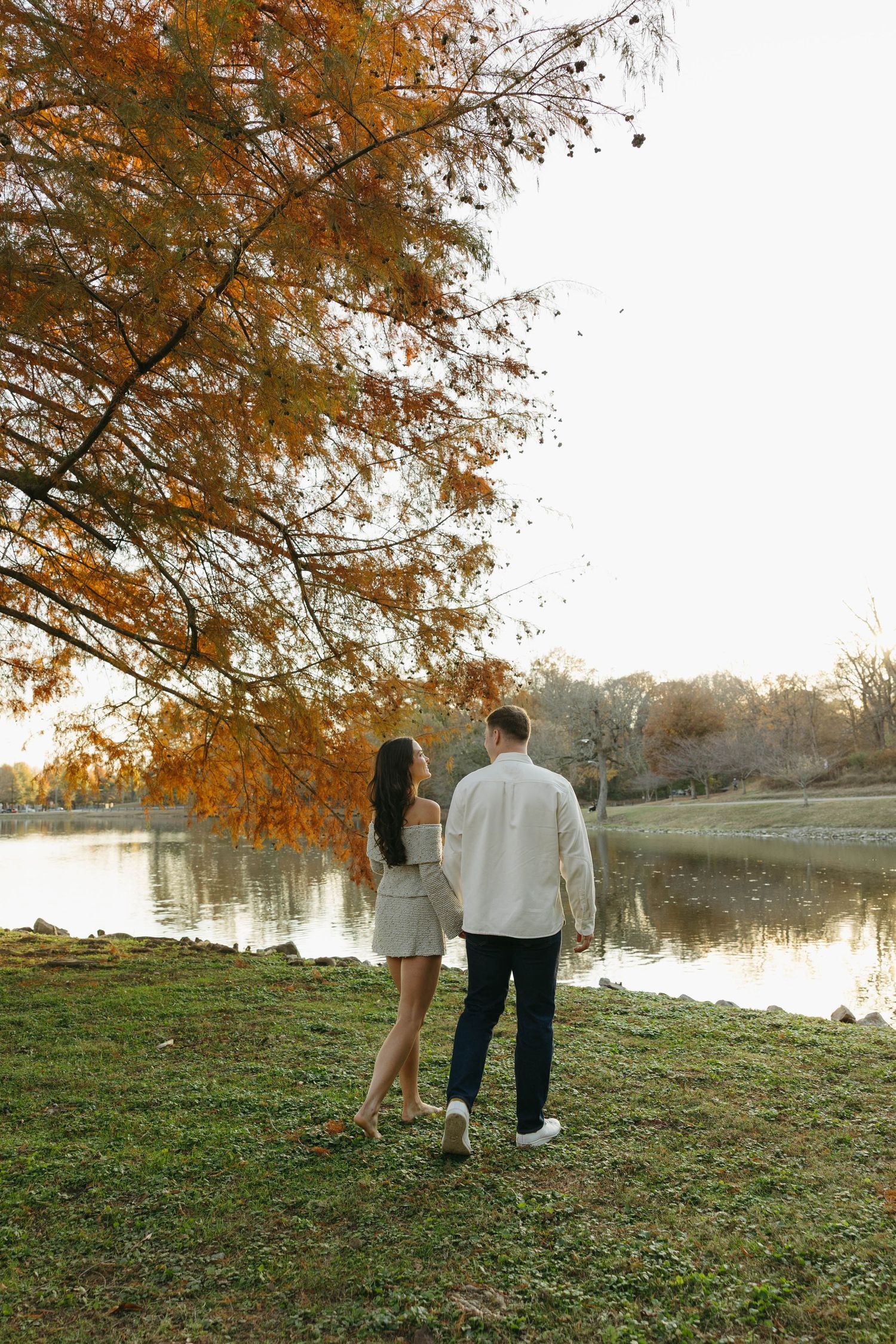 Birmingham Alabama Photographer capturing an engagement session of a couple walking in a park by a lake in Nashville Tennessee