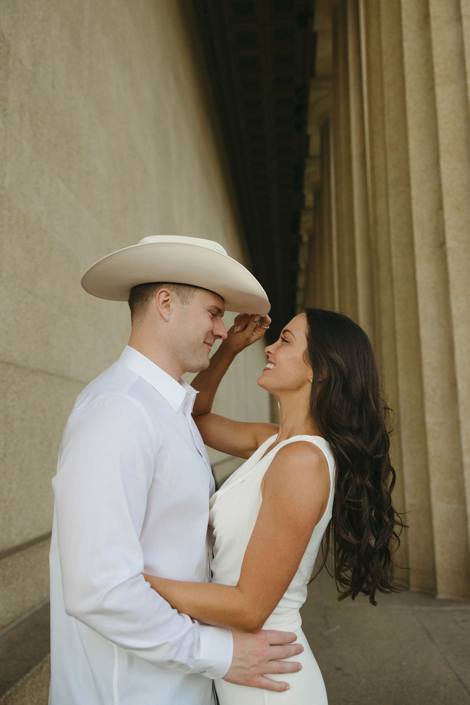 Birmingham Alabama Photographer capturing an engagement session of girl holding fiancé's cowboy hat in Nashville Tennessee at the Parthenon