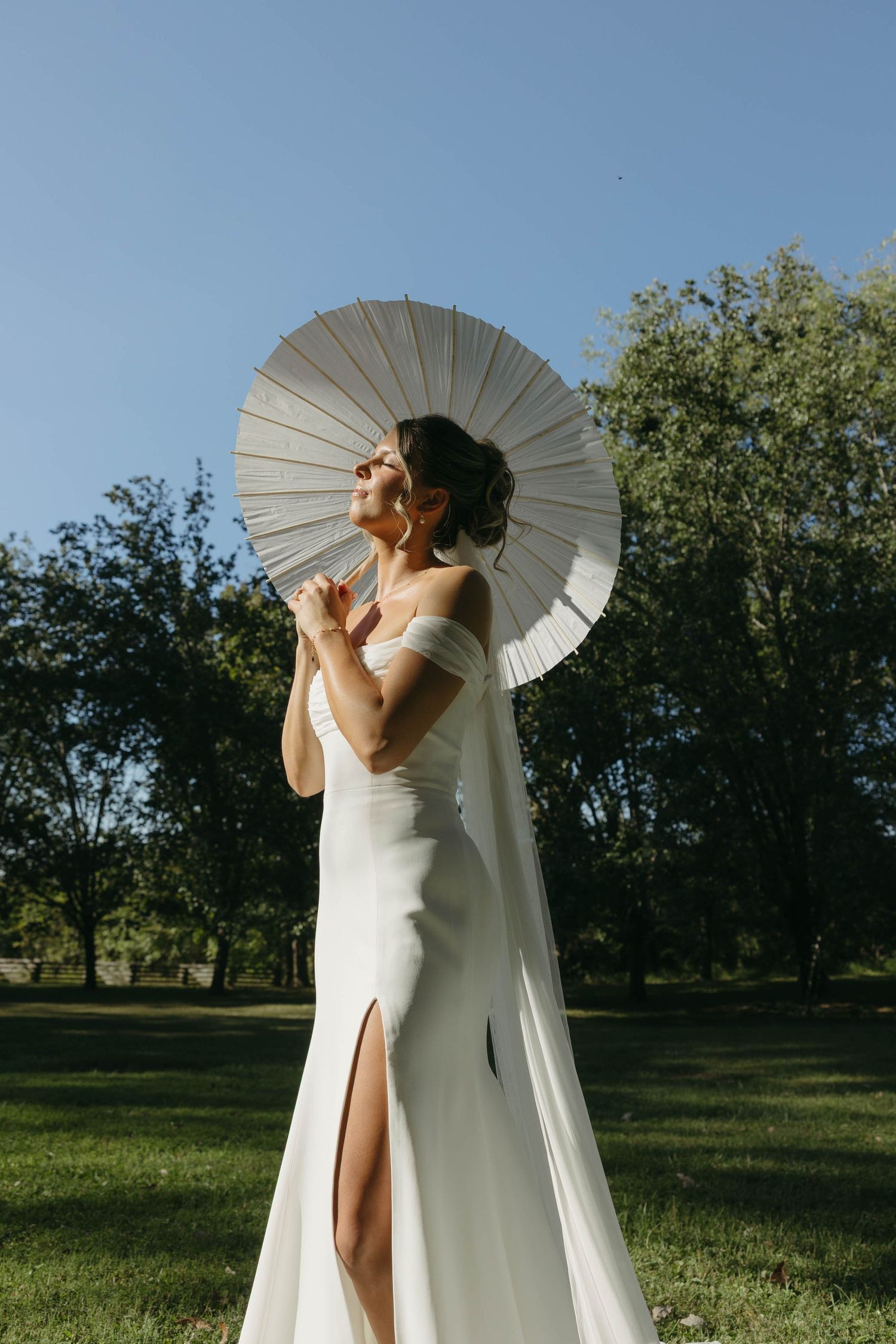 Birmingham Alabama Photographer capturing bride posing with her parasol, in the sun, at Iris Woods Venue in Nashville, Tennessee