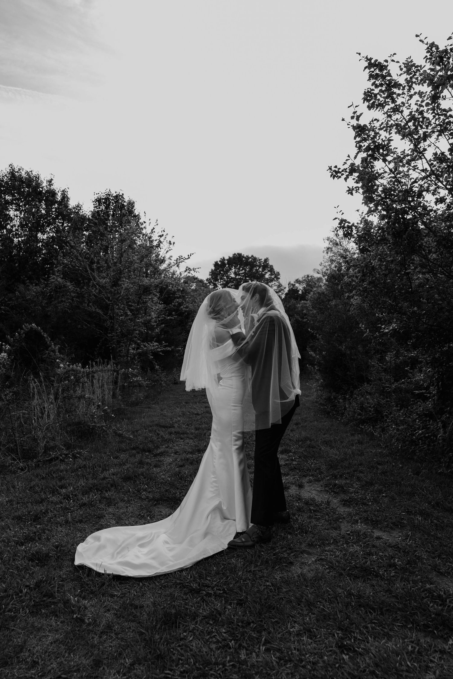 Birmingham Alabama Photographer capturing bride and groom posing under the veil, in a field, at Iris Woods Venue in Nashville, Tennessee
