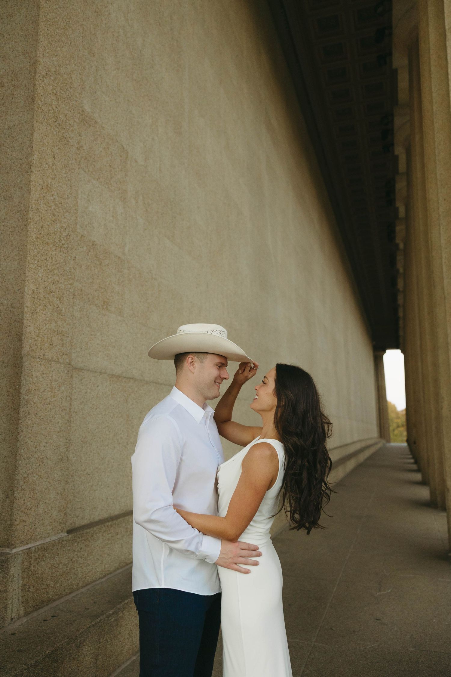 Birmingham Alabama Photographer capturing an engagement session of girl holding fiancé's cowboy hat in Nashville Tennessee at the Parthenon