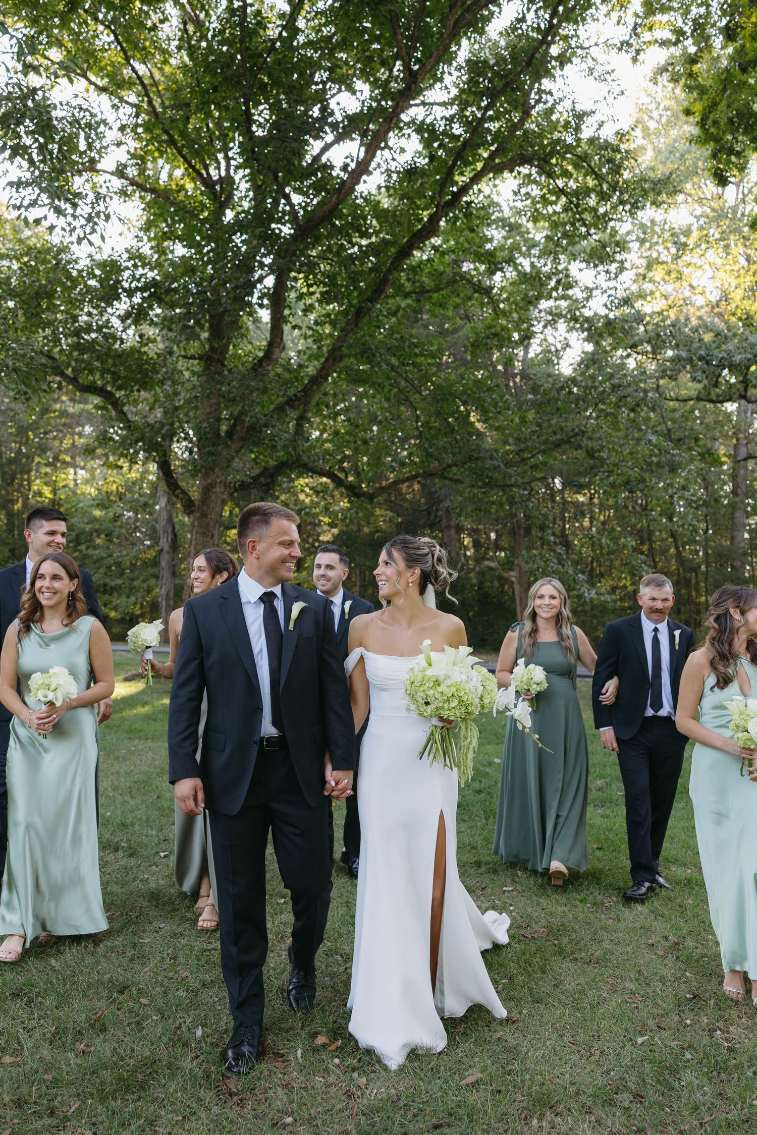 Birmingham Alabama Photographer capturing bride and groom walking in a field, with bridal party, at Iris Woods Venue in Nashville, Tennessee