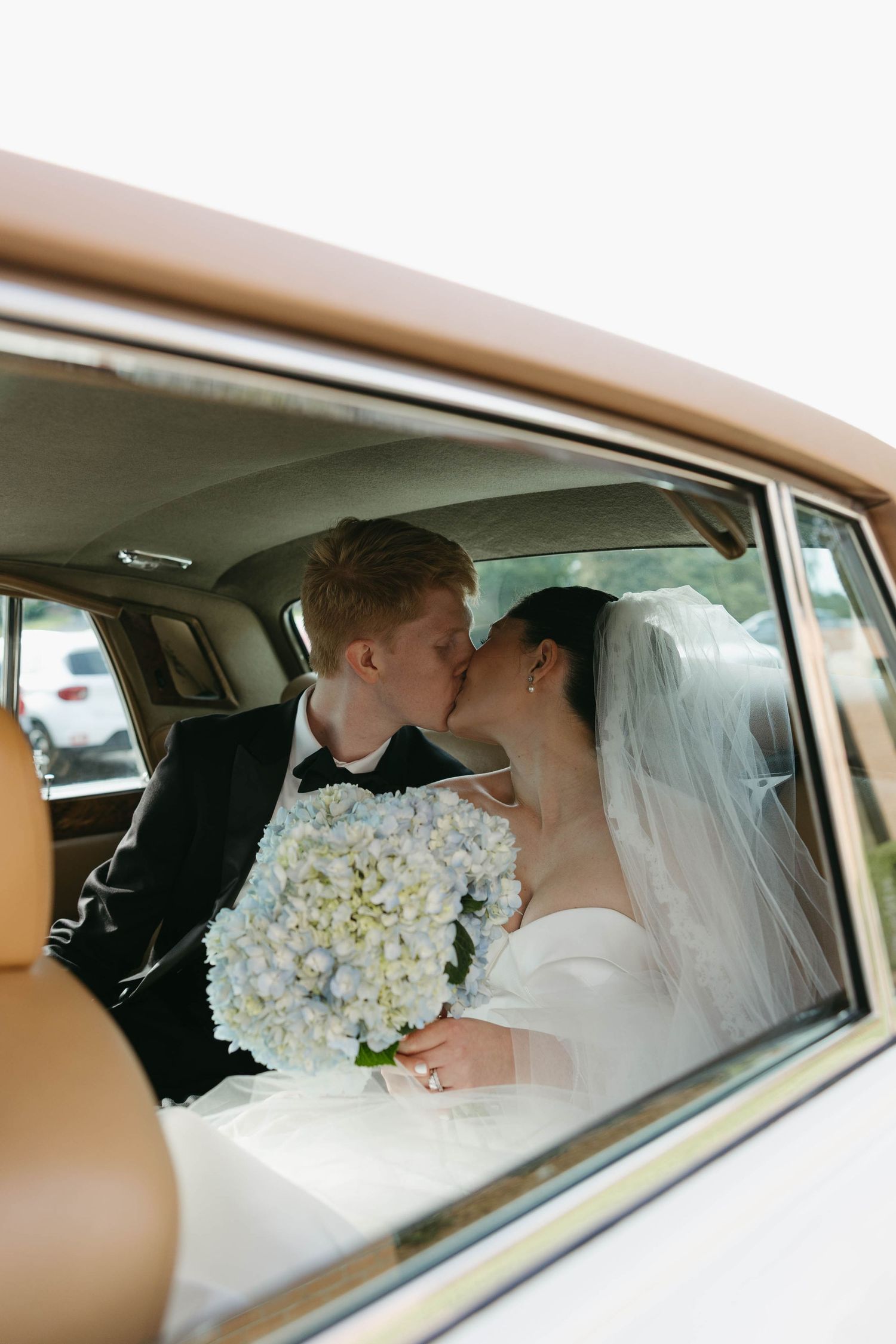 bride and groom kissing in old timey car