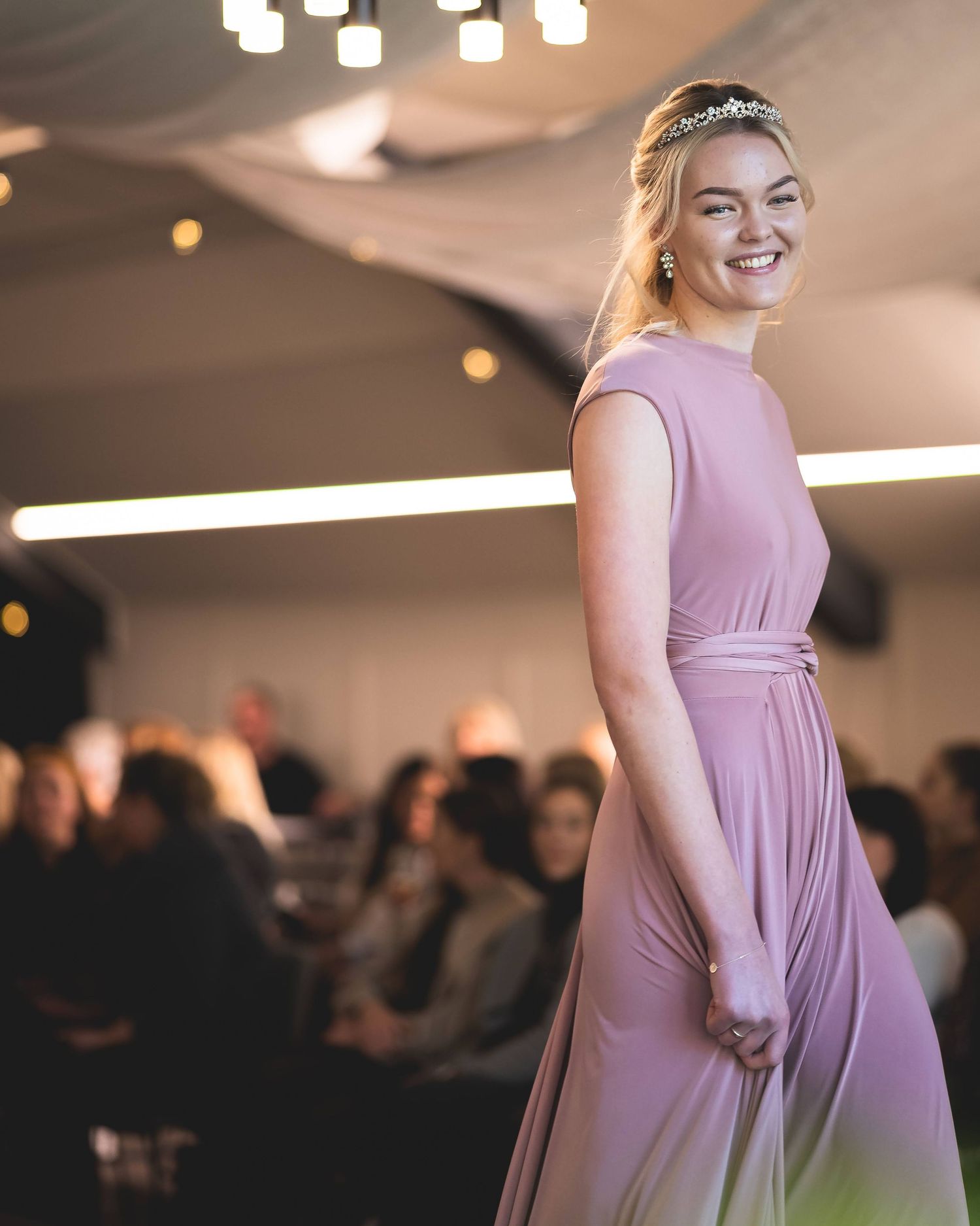 Moteshow – modell med rosa brudepikekjole på catwalk med myk belysning