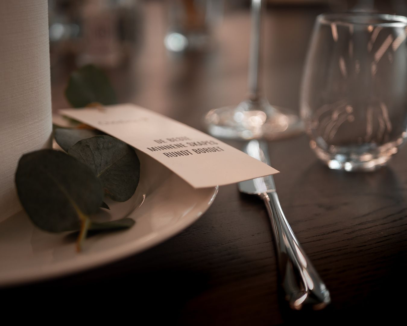 Restaurantdetaljer – mørkt bord med vinglass og regning i stemningslys