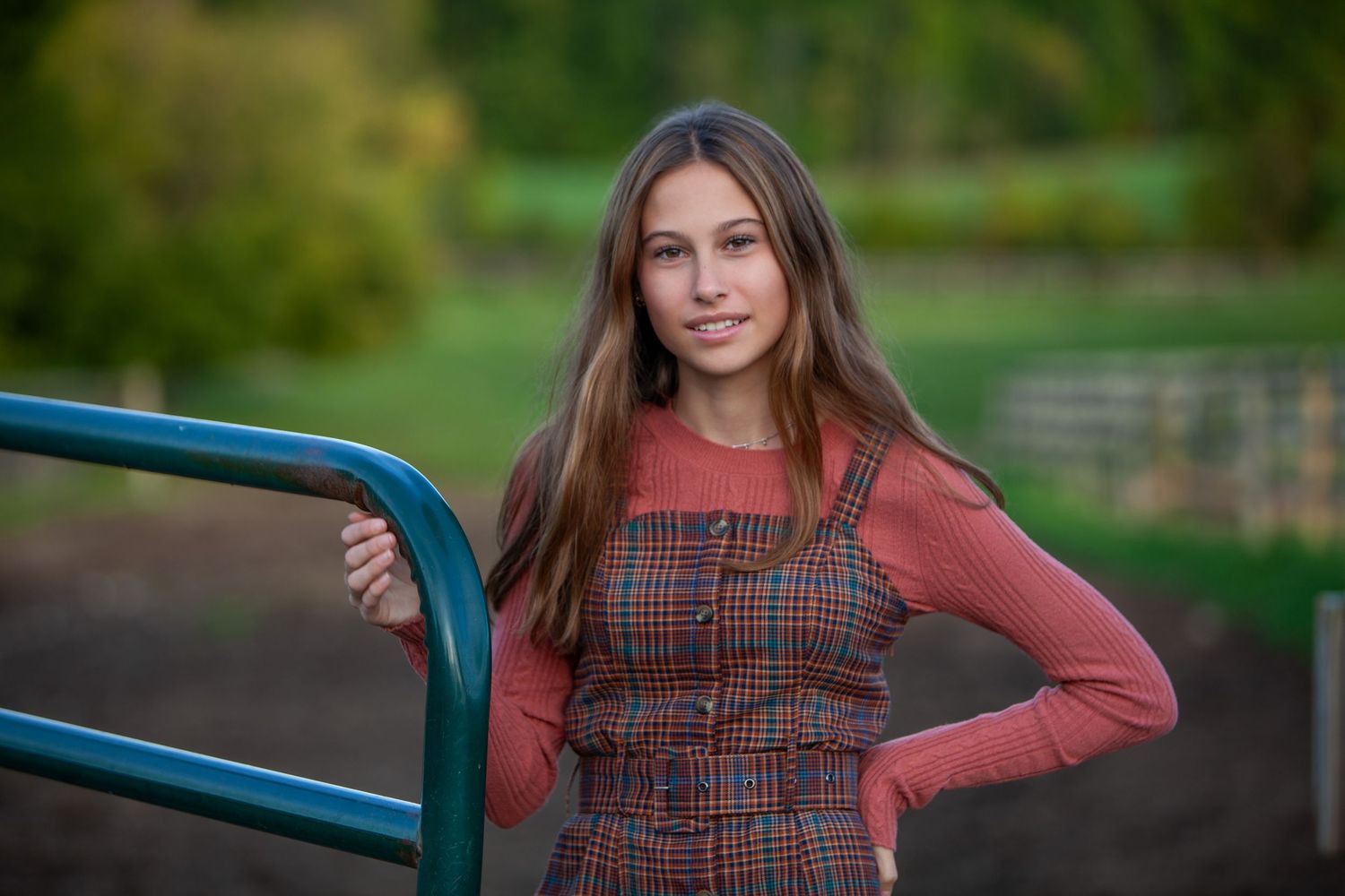 Pre-teen milestone portrait in Rochester, MI by Jocelyn M. Photography—young girl in plaid dress by a green gate.