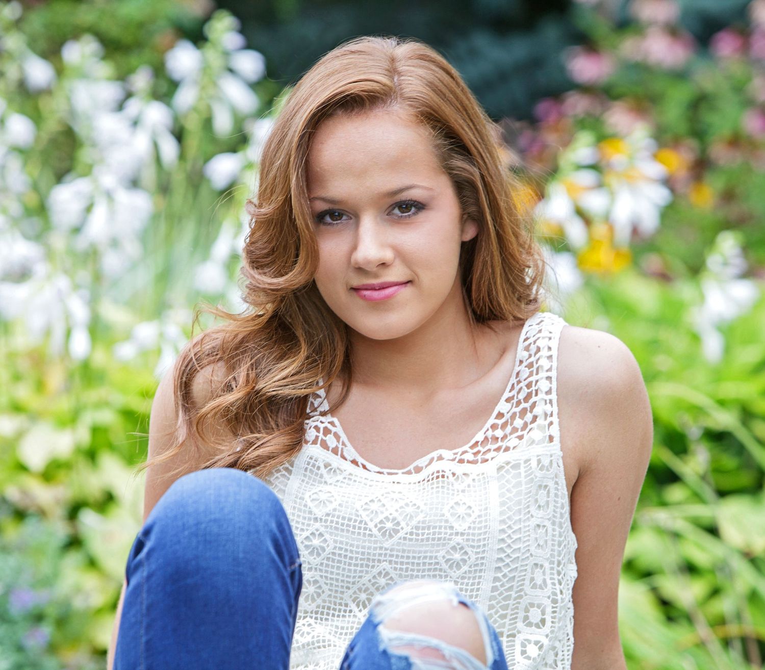 Senior portrait sitting outdoors among colorful garden flower, by Jocelyn M. Photography in Rochester, MI