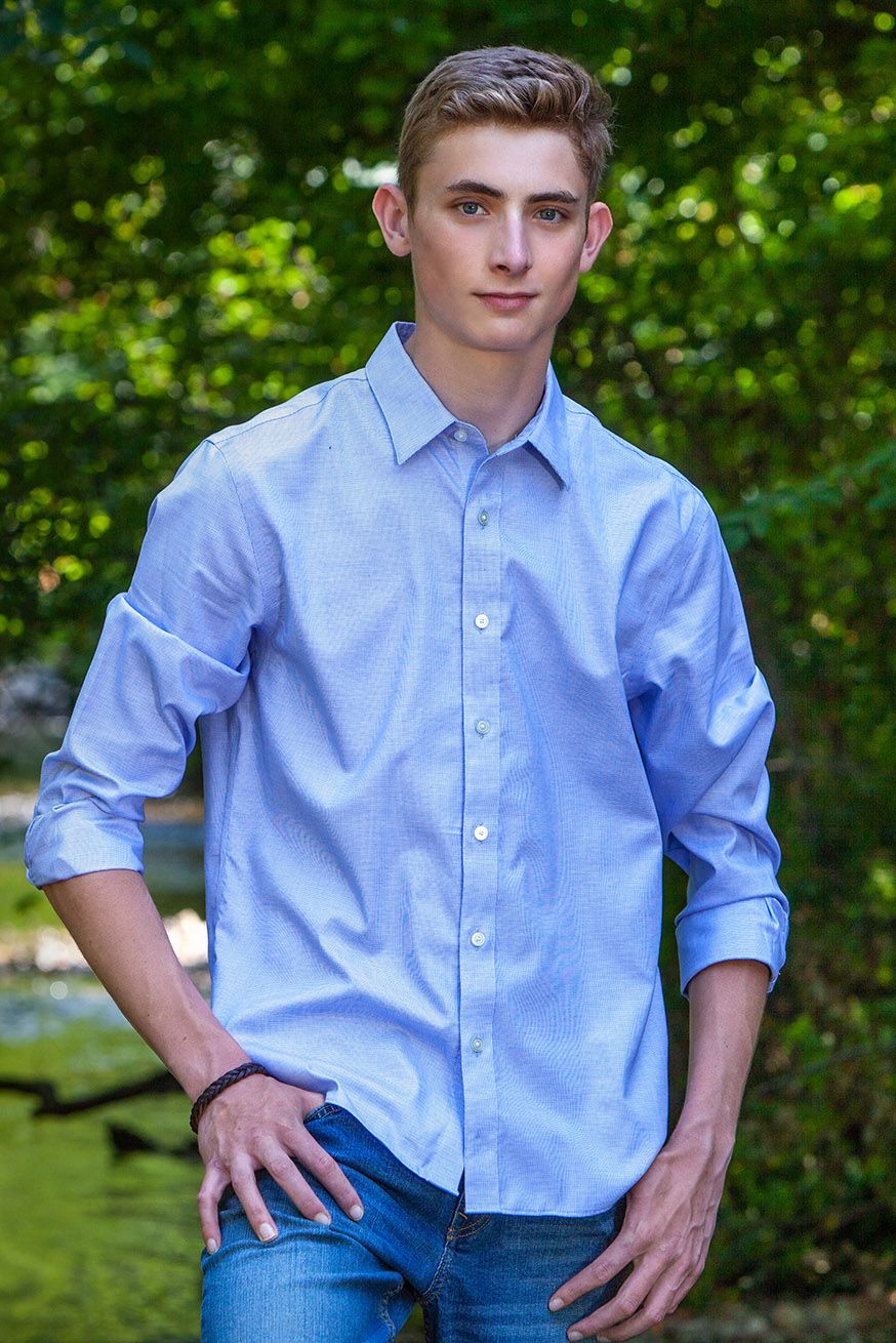 Outdoor senior session in Rochester, MI by Jocelyn M. Photography—young man posing with green trees in background.