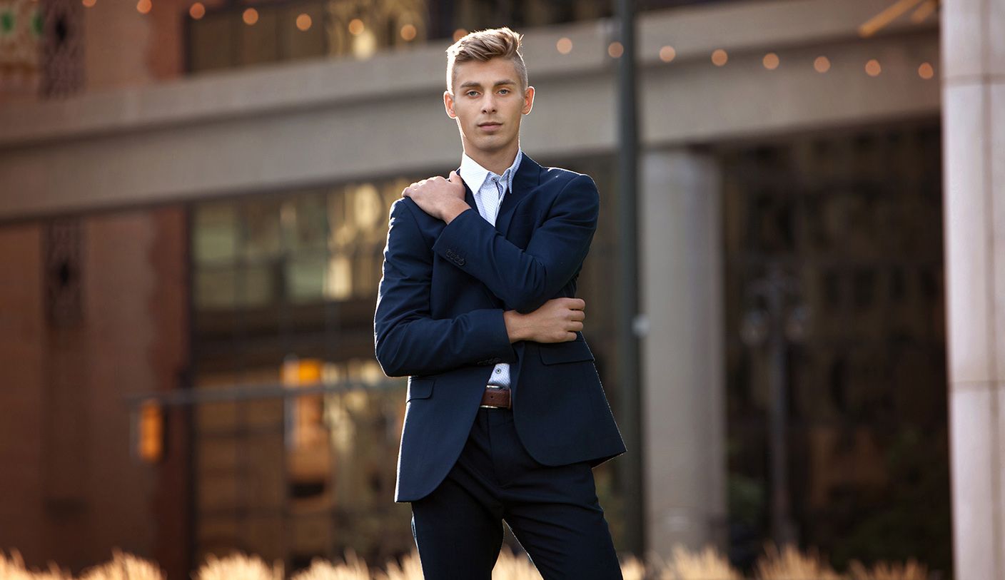 Guys senior portrait session in Rochester, MI by Jocelyn M. Photography—young man in navy blue suit with urban bokeh.