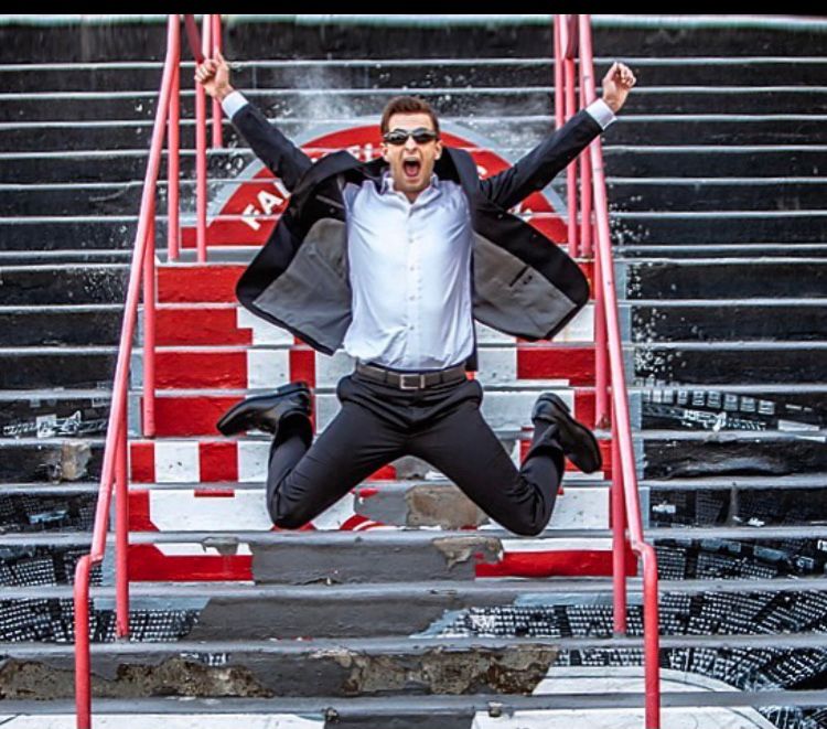 Creative senior portrait session in Rochester, MI by Jocelyn M. Photography—excited young man jumping on stadium stairs.