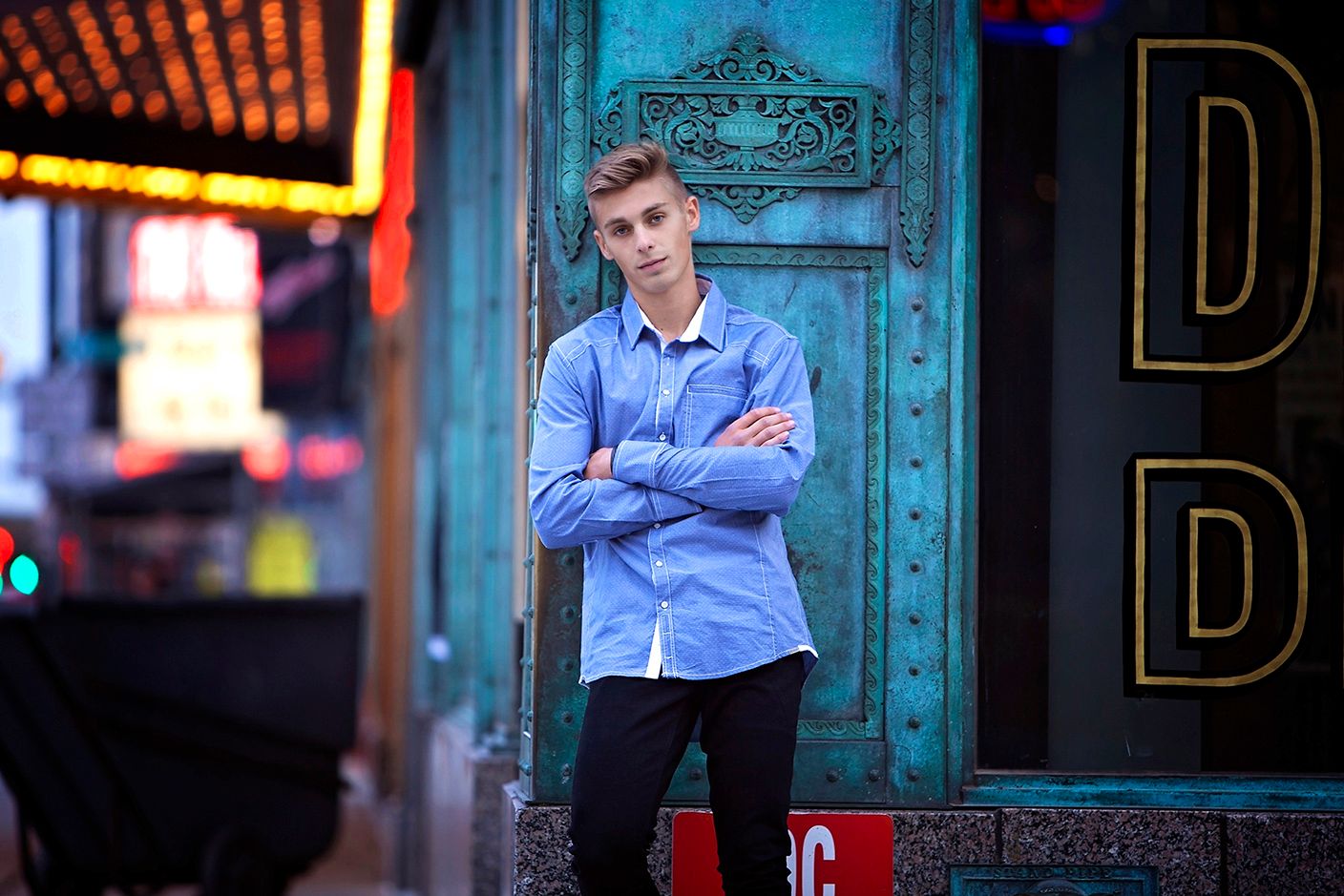 Urban senior portraits in Rochester, MI by Jocelyn M. Photography—young man with arms crossed before a vintage teal door.