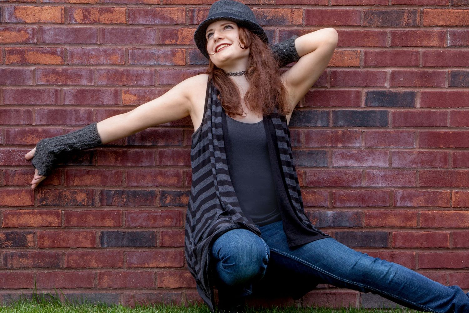Senior girl in striped cardigan and hat posing against red brick wall outdoors, by Jocelyn M. Photography in Rochester, MI