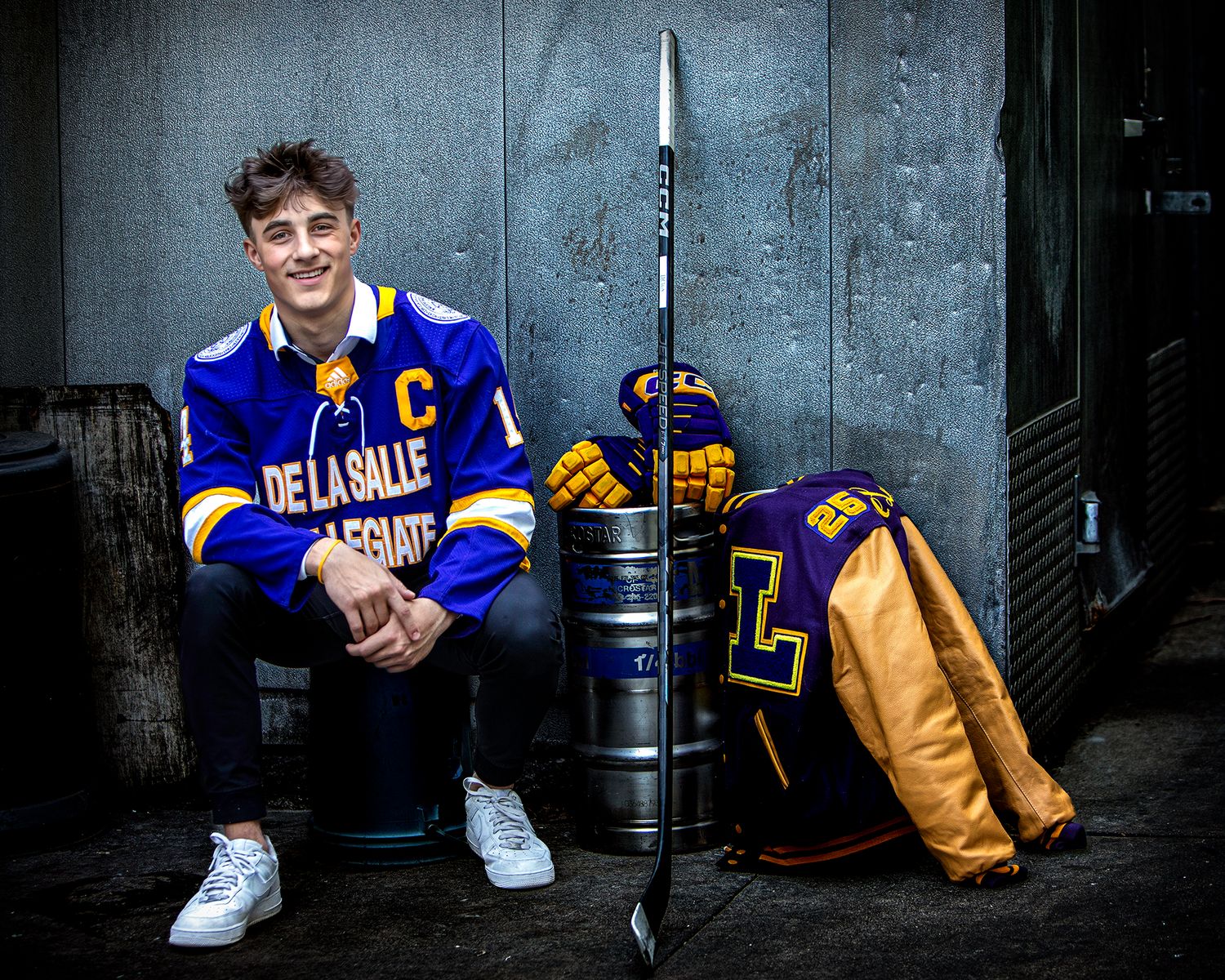 De La Salle hockey senior portrait in Rochester, MI by Jocelyn M. Photography—athlete posing in studio with gear.