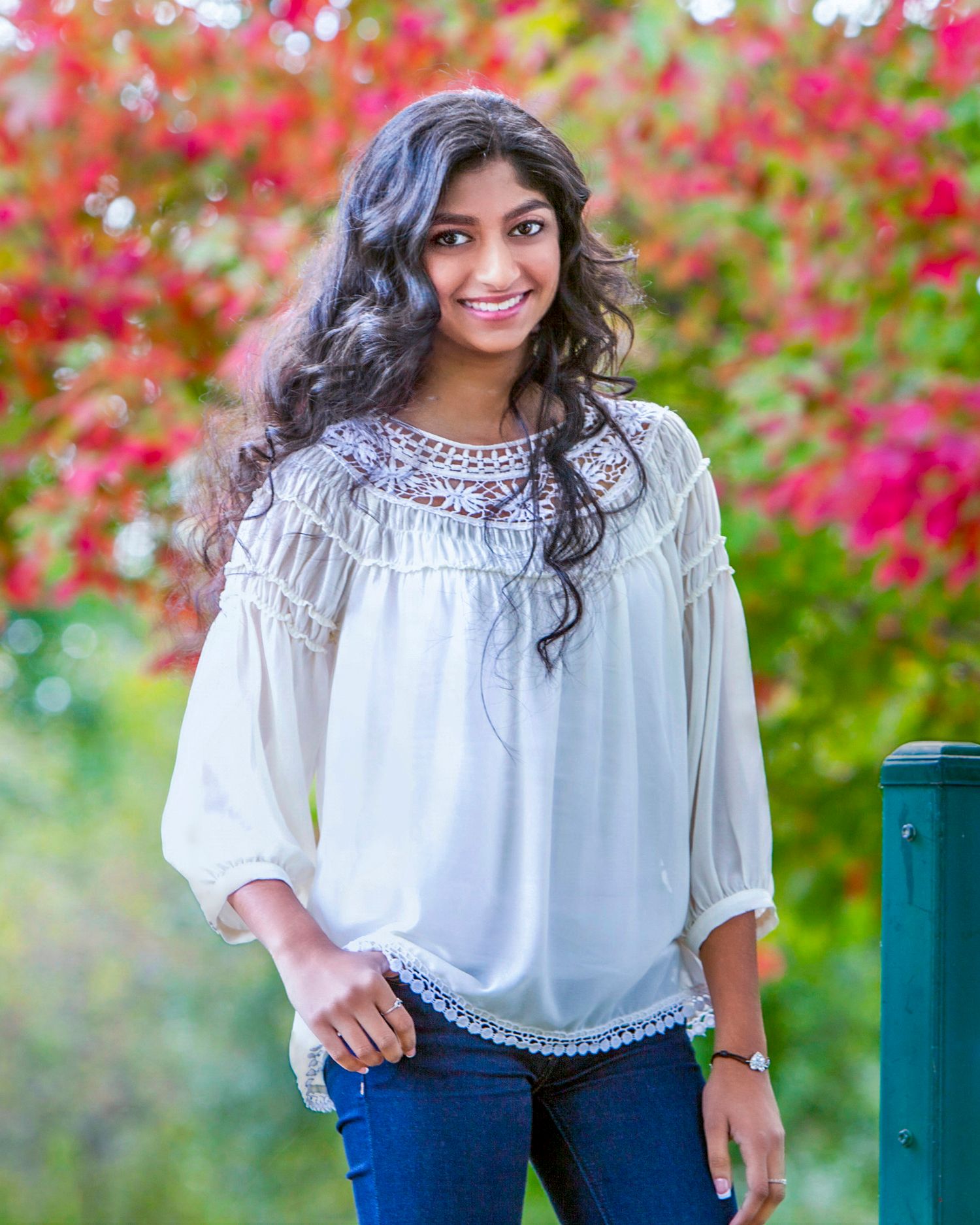 Senior girl smiling outdoors with colorful autumn foliage background, by Jocelyn M. Photography in Rochester, MI