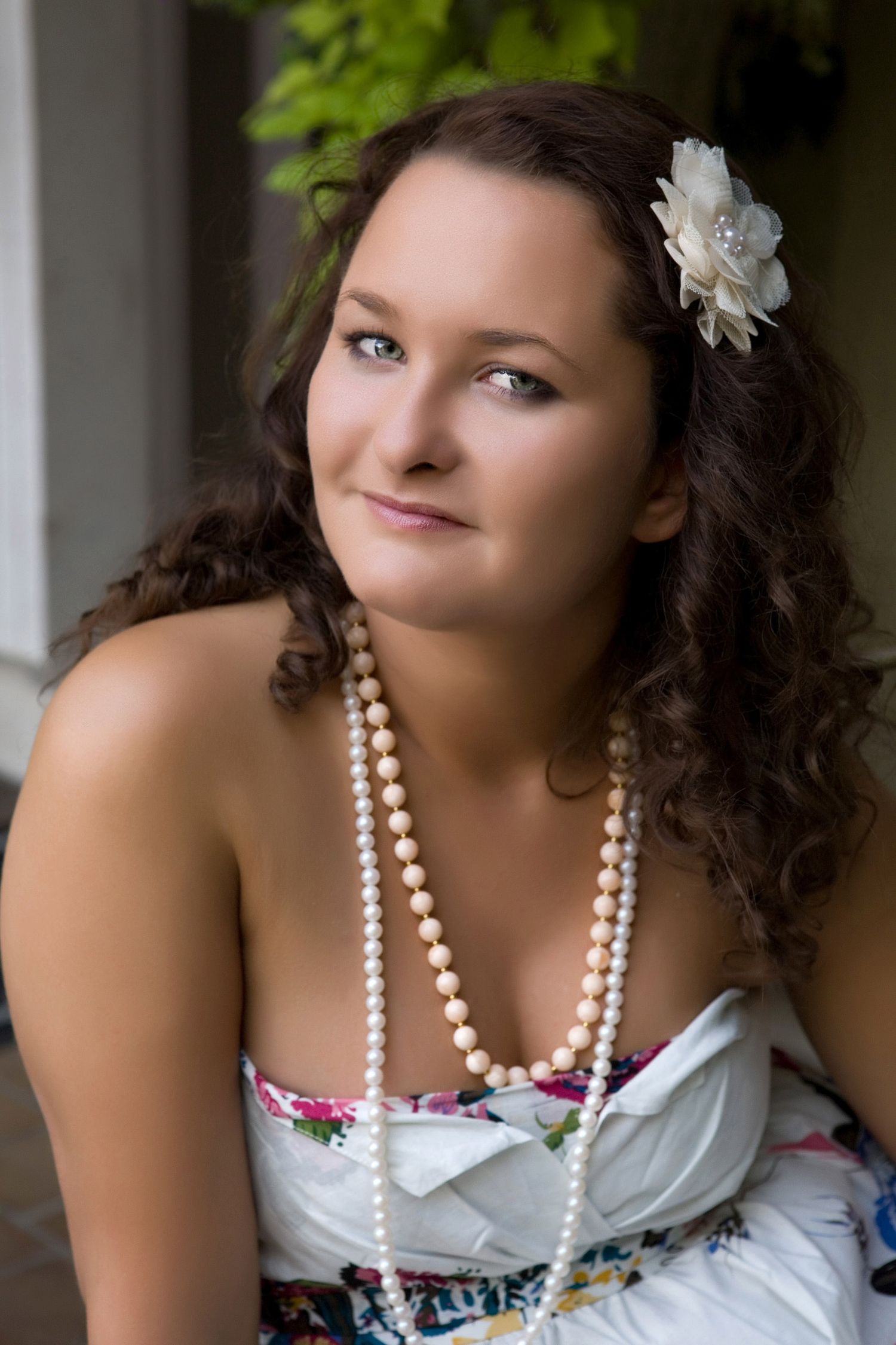 Senior girl with curly dark hair wearing a pearl necklaceby Jocelyn M. Photography in Rochester, MI,